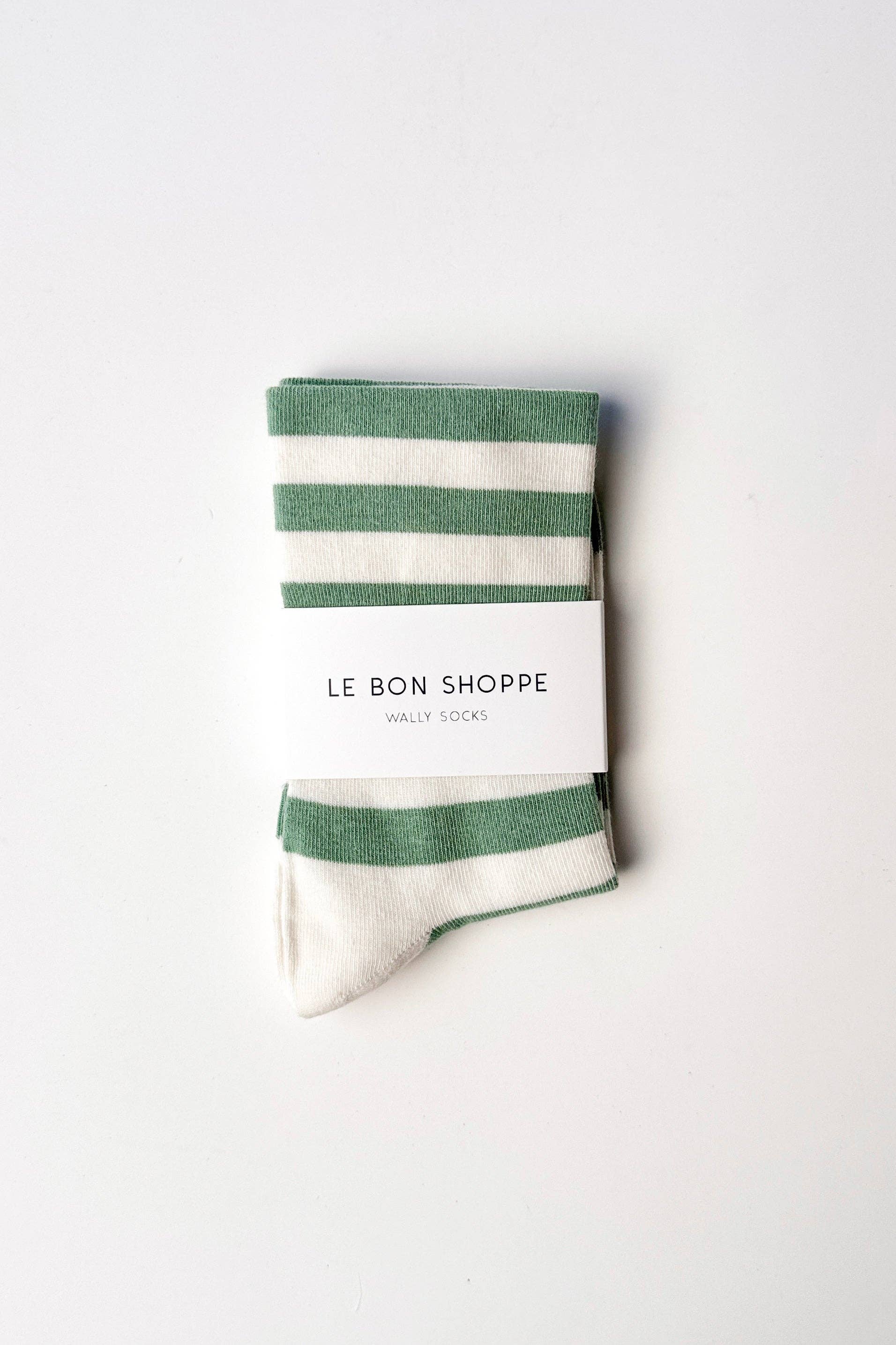 Green and white striped socks with 'Le Bon Shoppe' packaging on a white background