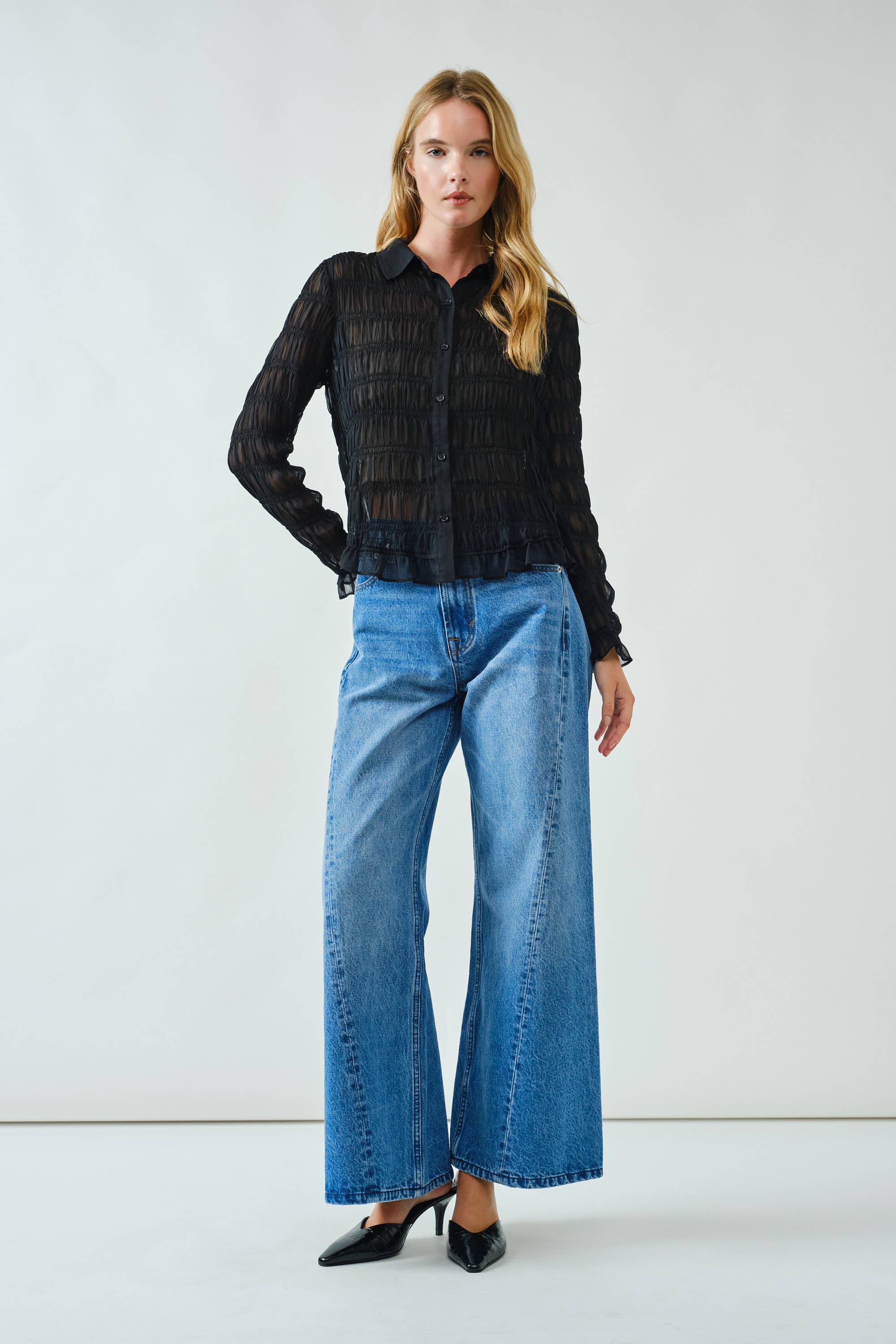 Woman wearing a black shirt and blue jeans against a white background