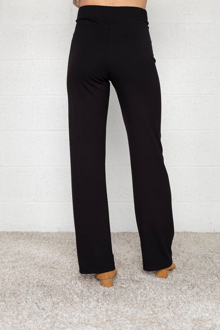 Woman wearing flats and black Micah pants that are skinny on the top with wide bottom