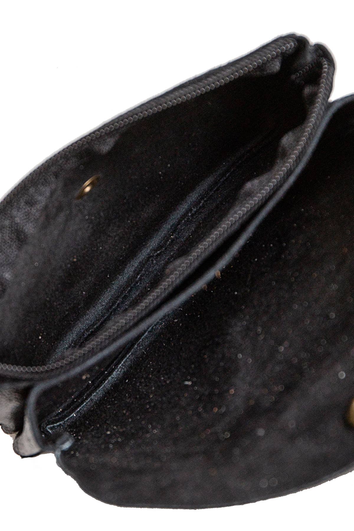 Close-up of the interior of a black fabric pouch or clutch bag, showing the lining, zipper edge, and a small brass grommet on a white background.