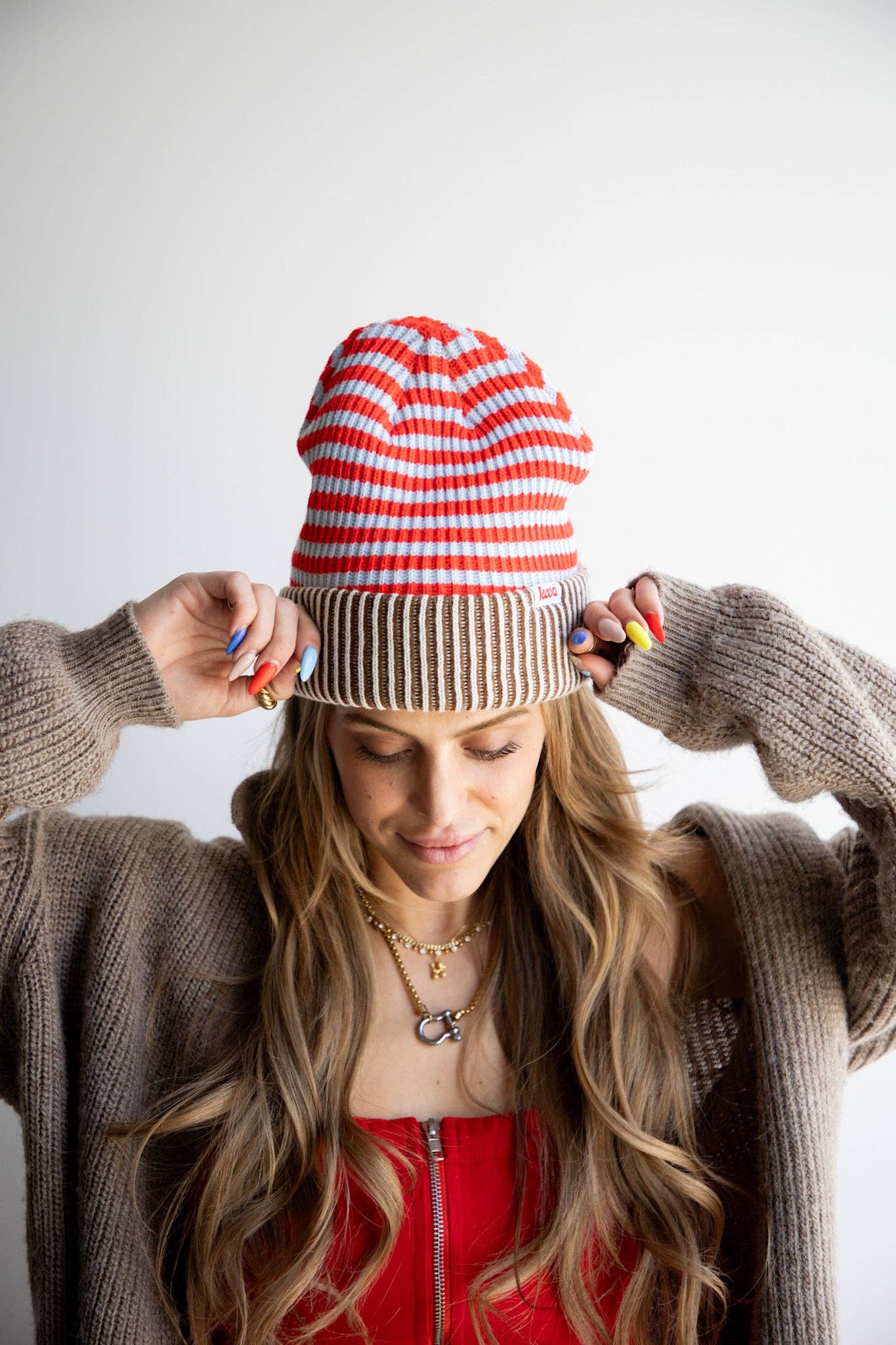 Woman wearing a red and white striped beanie with a plain background