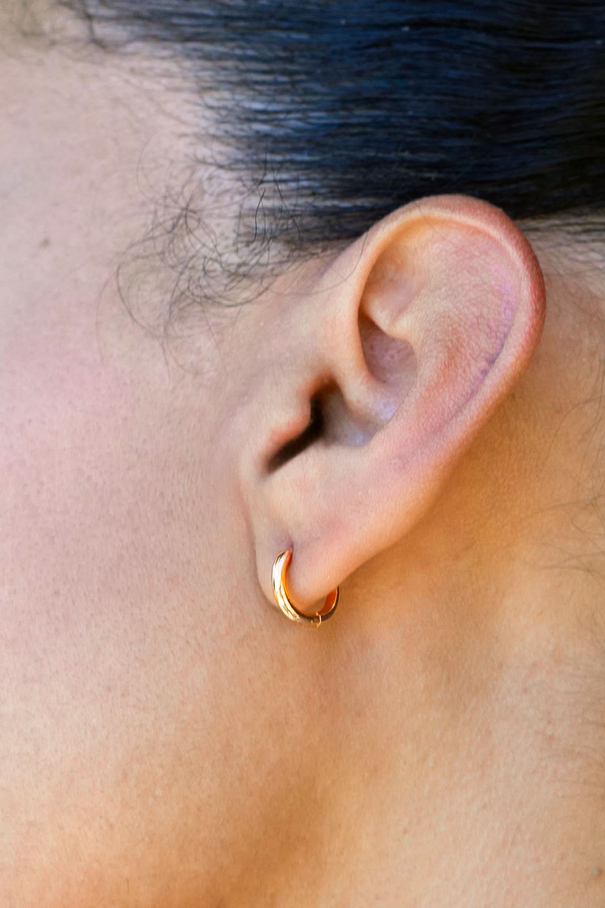 Woman wearing the everyday gold Huggies medium sized hoops