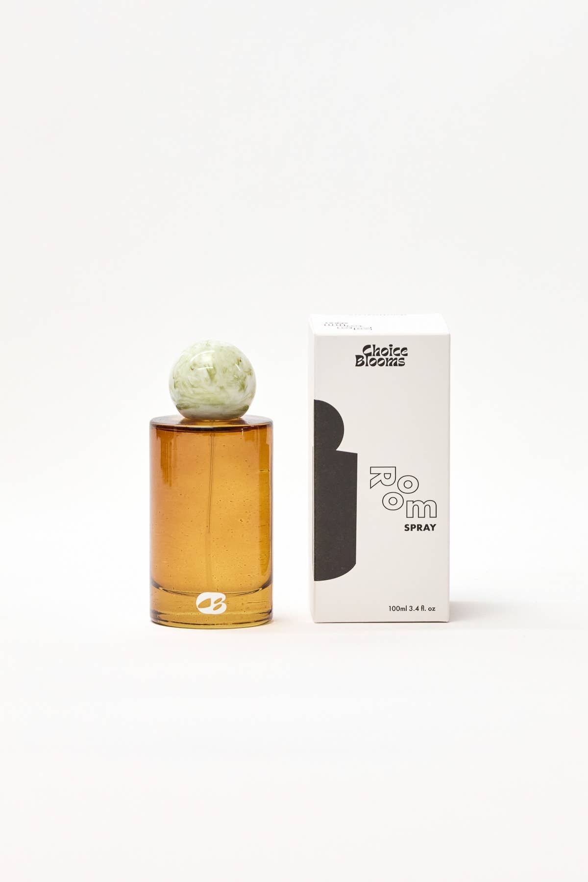 Amber glass perfume bottle with decorative cap next to its packaging on a white background