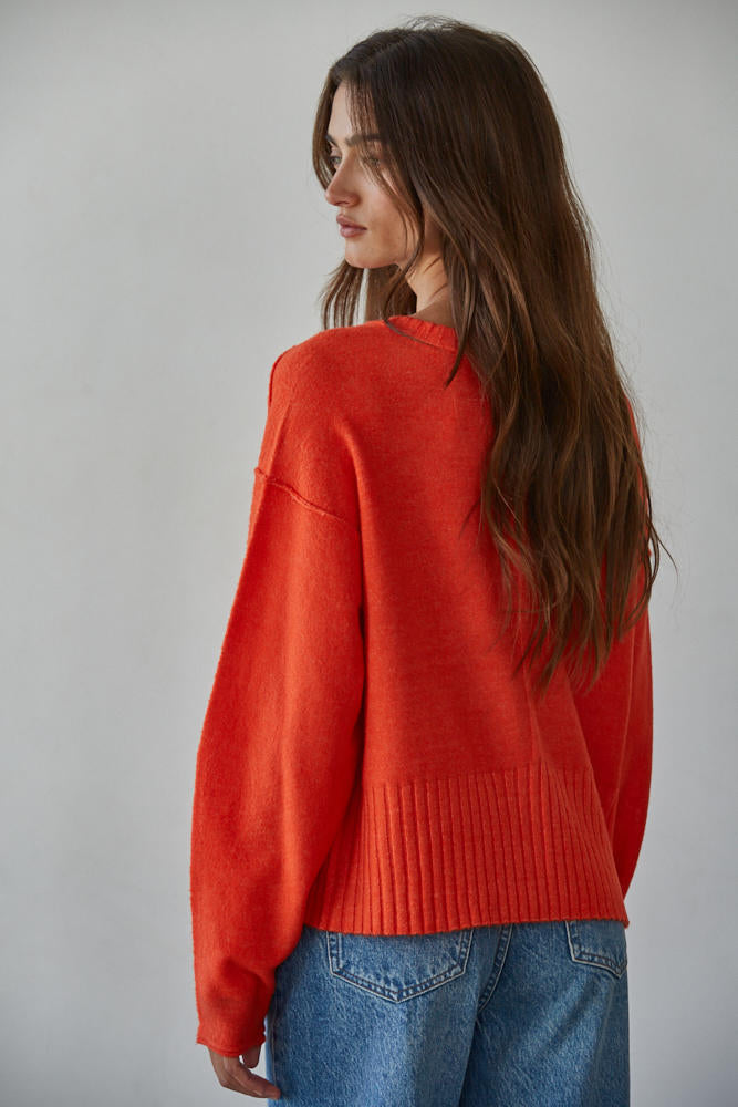 Woman wearing a red sweater and blue jeans.