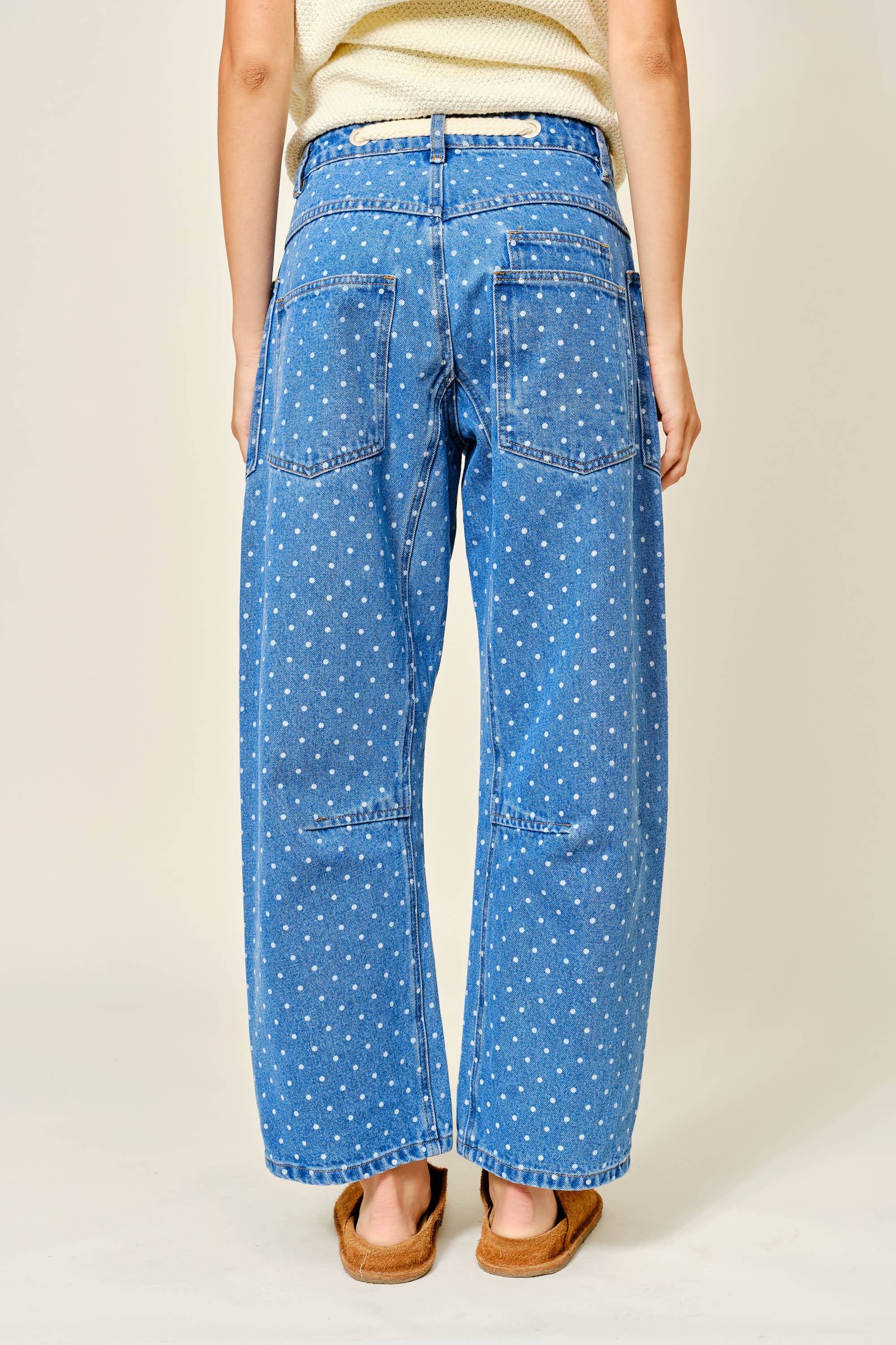 Person wearing blue polka dot pants on a plain background