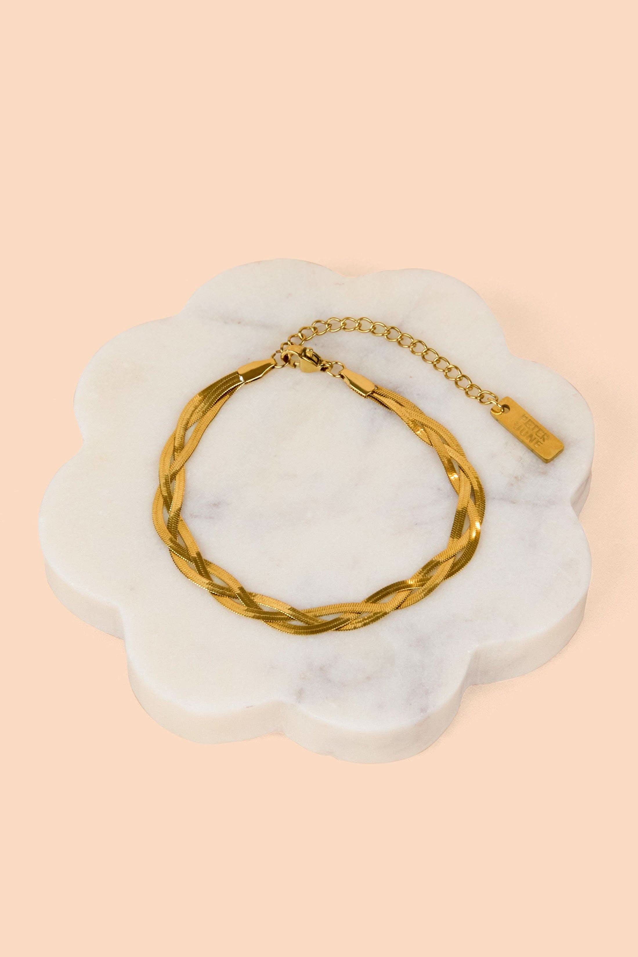 Gold bracelet on a white marble surface with a beige background