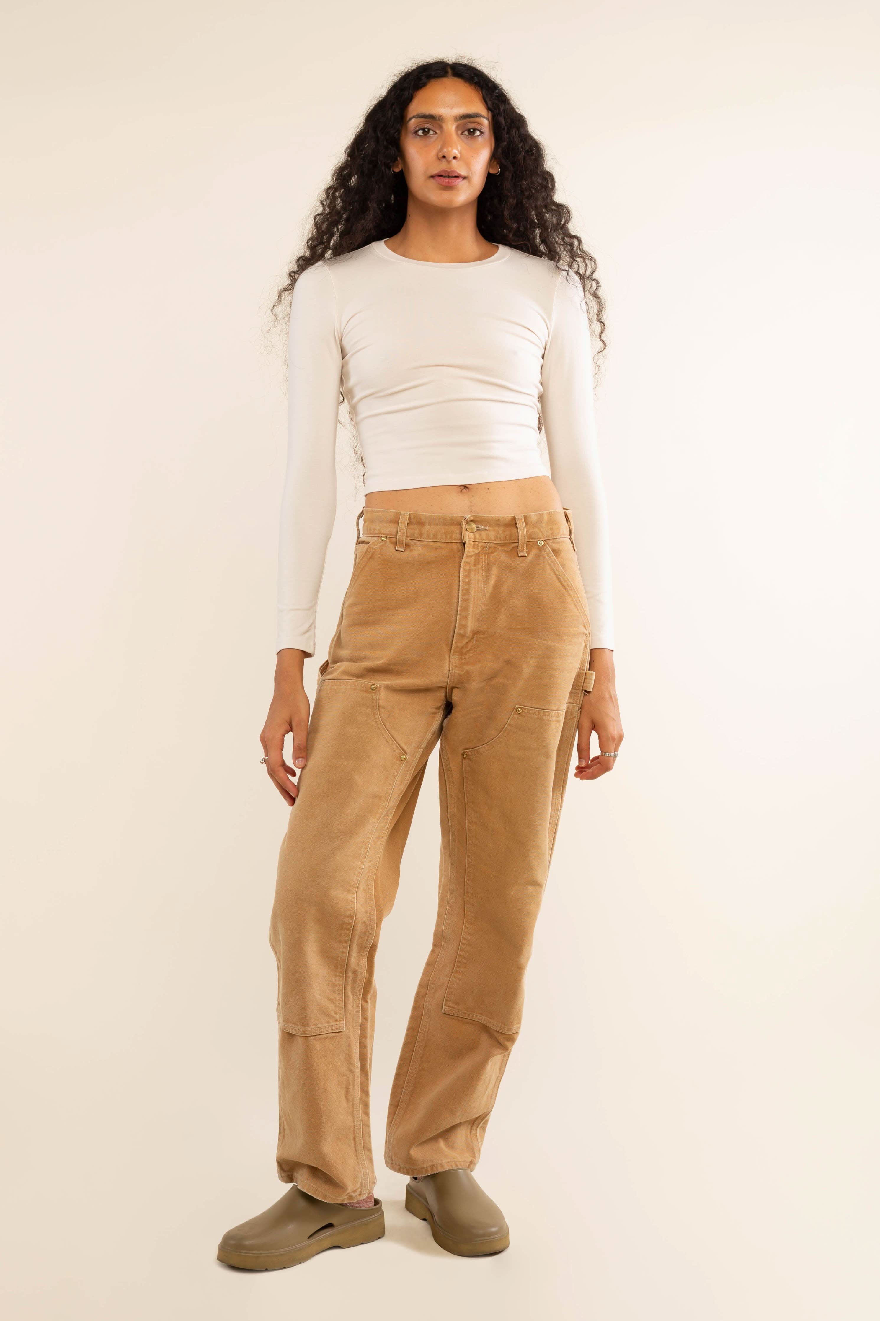 Woman wearing white, long sleeve, tight, crew neck, top with khaki jeans