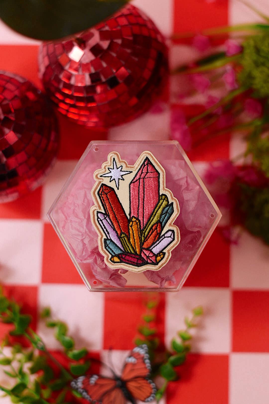Hexagonal crystal patch on a red and white checkered background with decorative items.