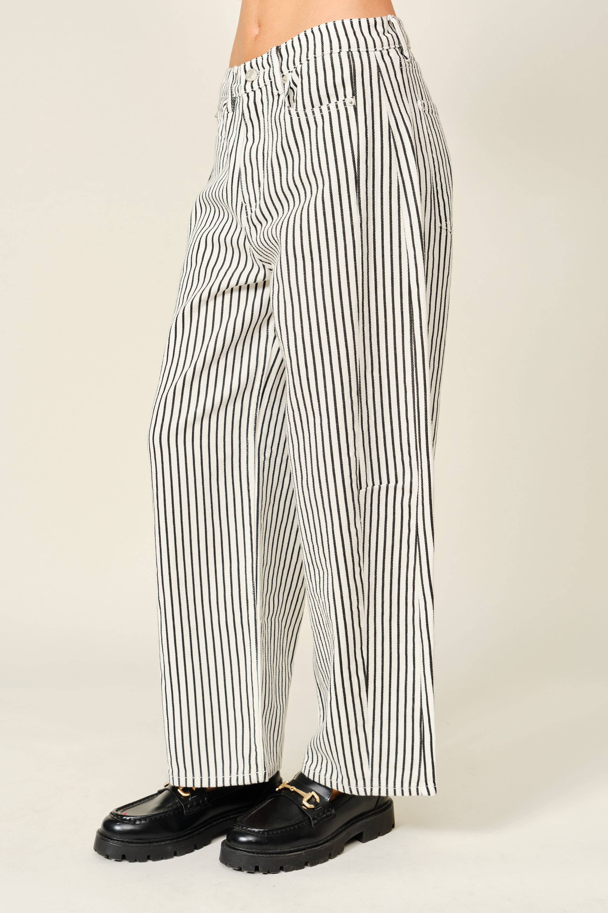 Black and white striped pants worn by a person on a beige background
