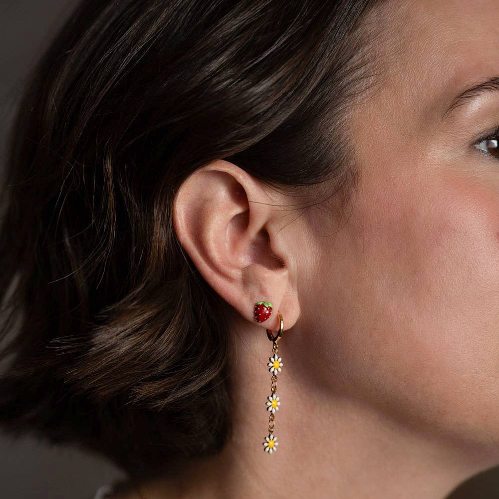 Woman wearing strawberry stud earrings in second piercing with long daisy earrings in first piercing 