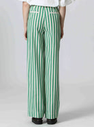 Woman wearing white shirt and green and white, vertically striped pants
