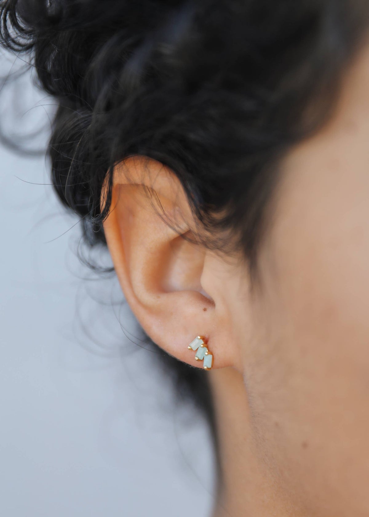 Close-up of an ear wearing a small earring with a blurred background