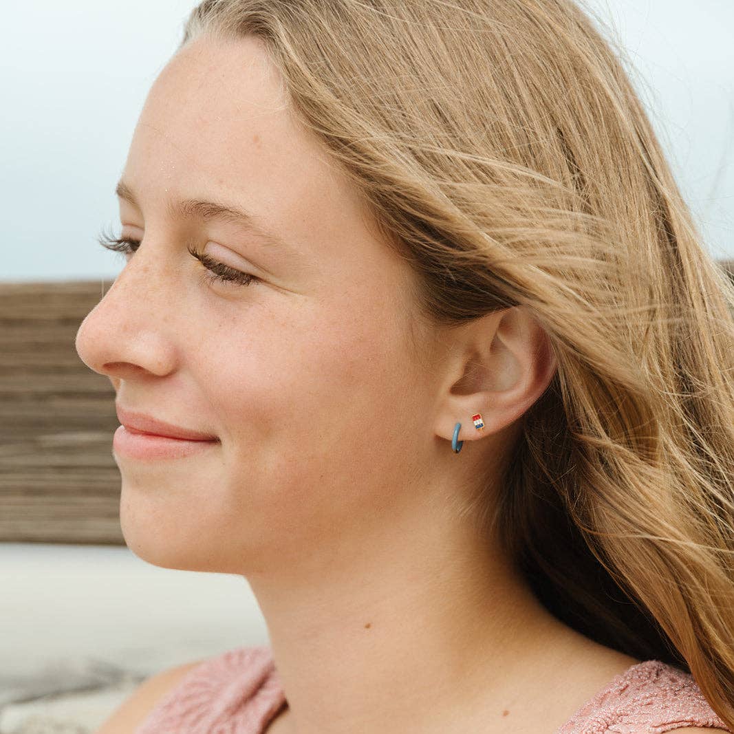 Woman wearing Pair of red,white, and blue popsicles bomb pop, flat-back gold earrings