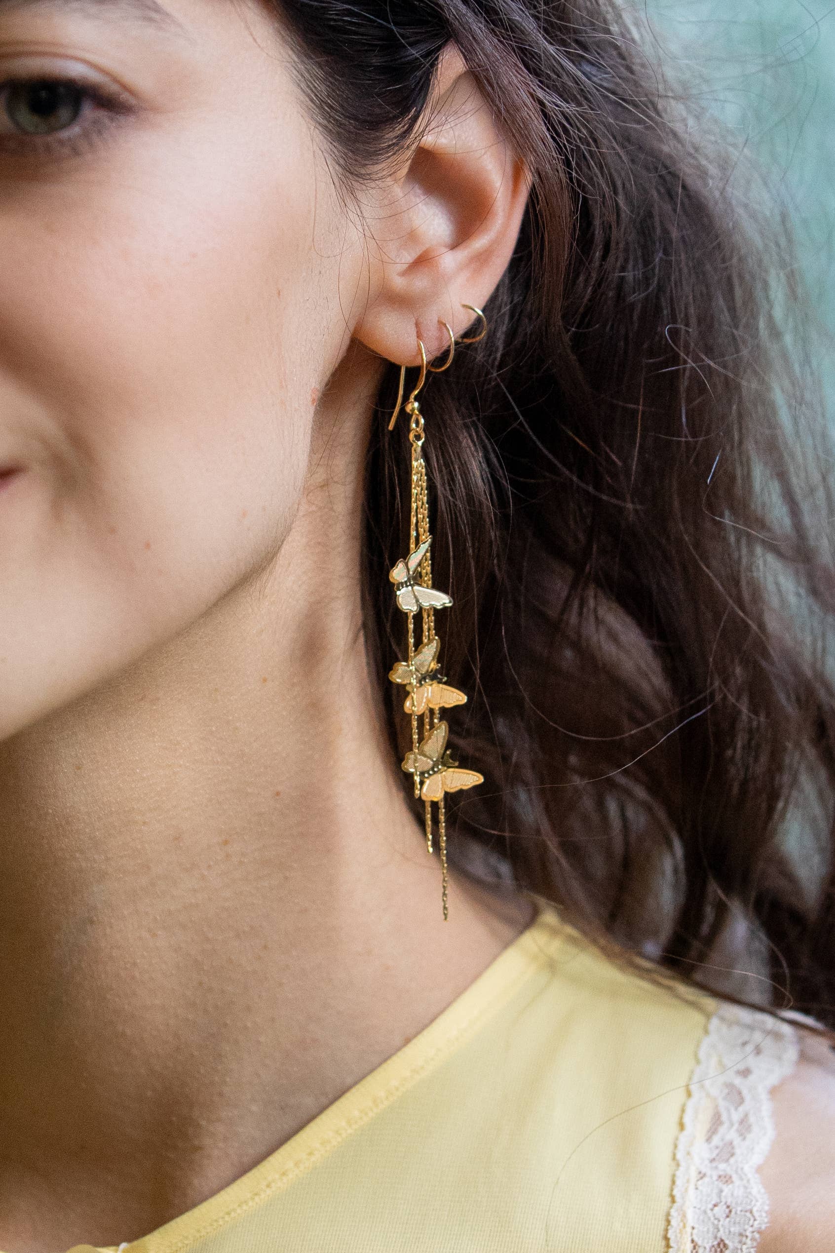 woman wearing gold butterflies dripping chain earrings 