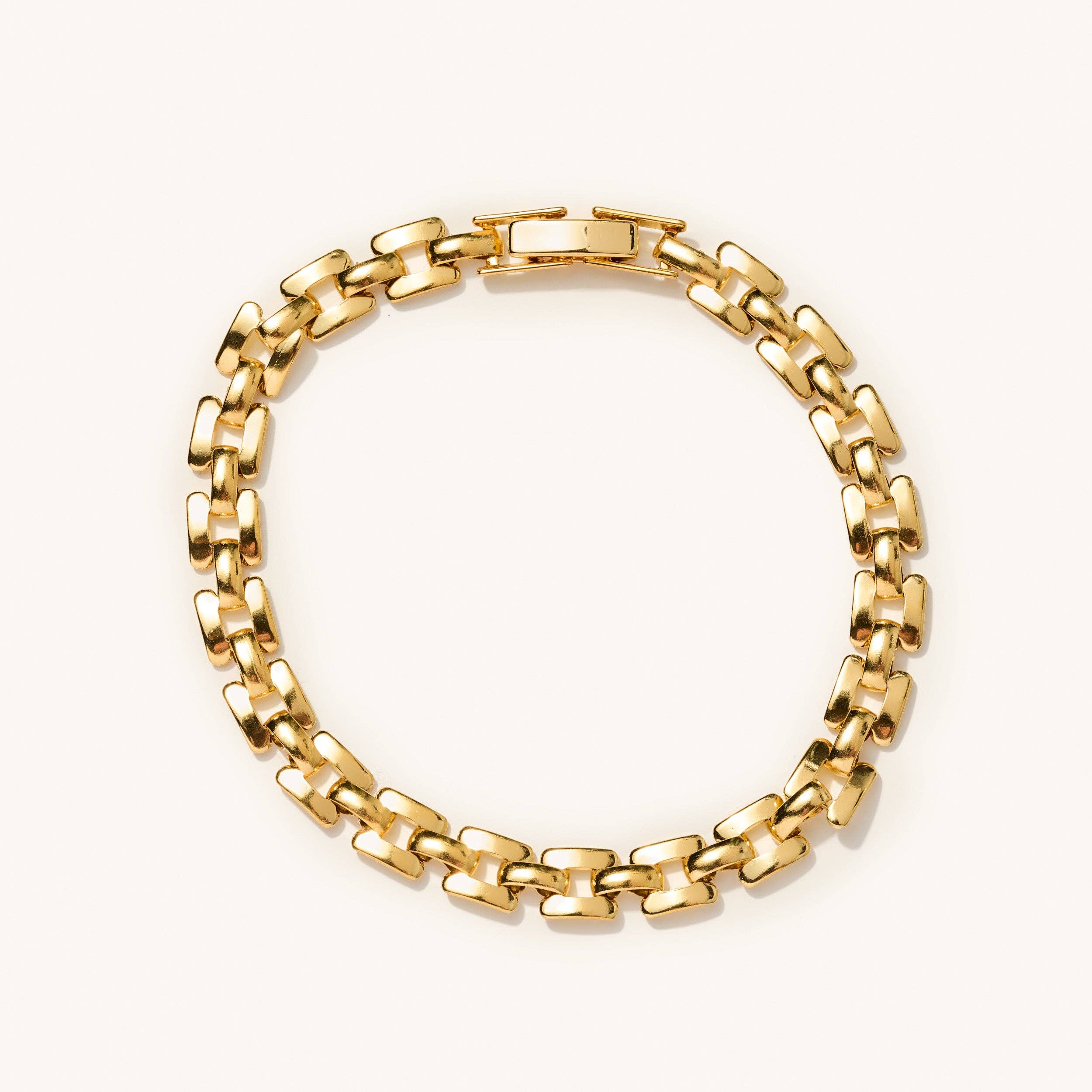 Lightweight gold watch strap bracelet laying flat on a white background 