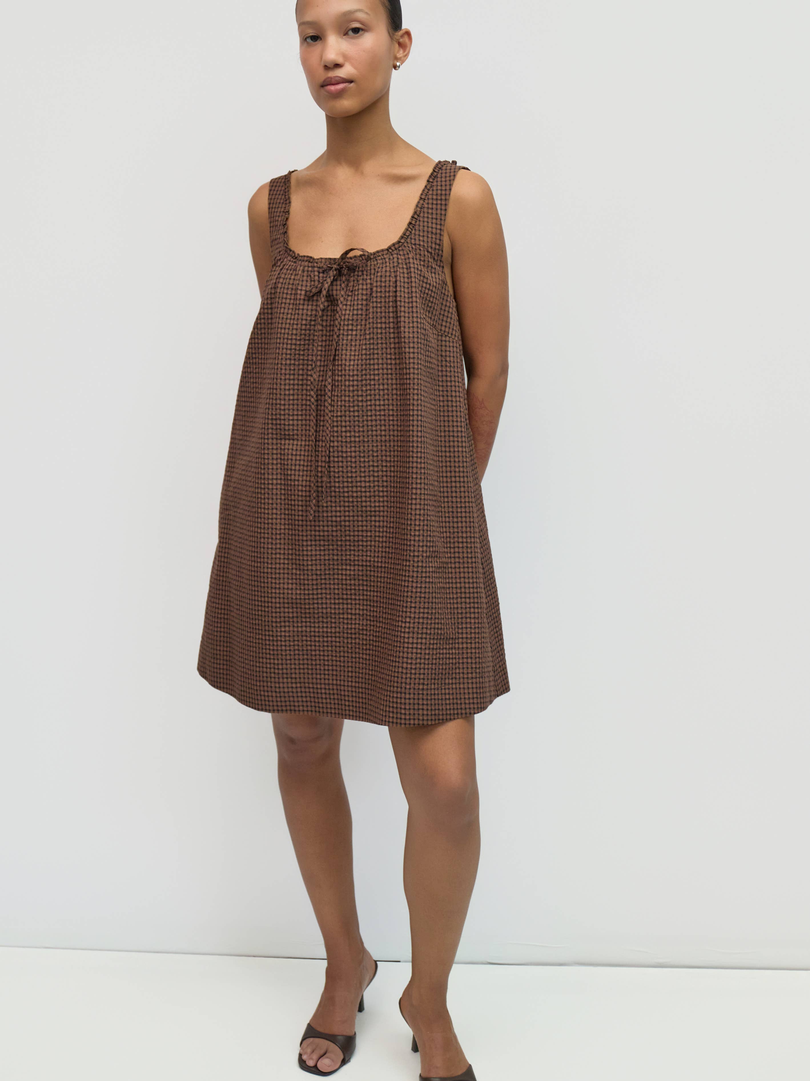 Woman wearing a brown checkered dress against a white background