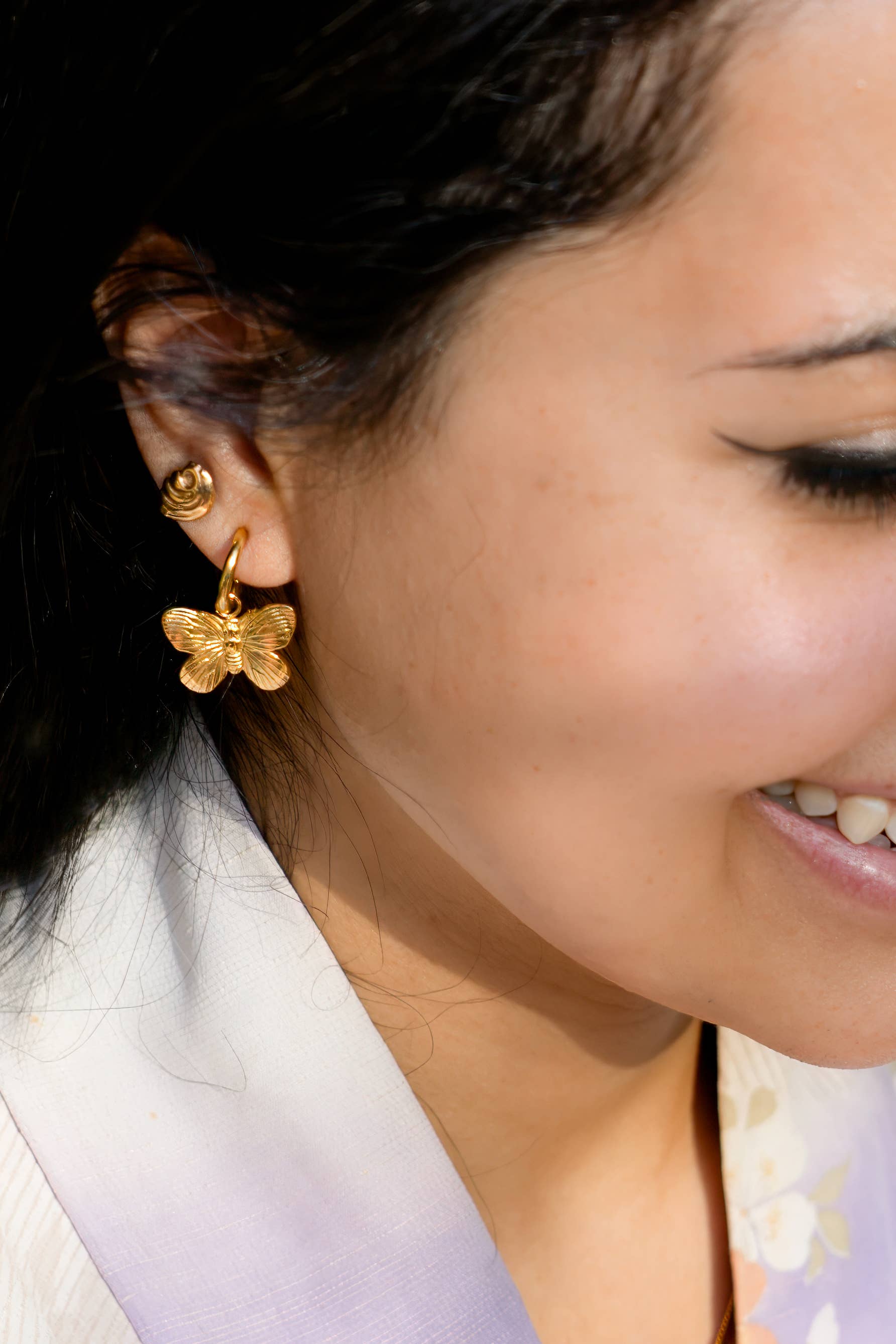 Woman wearing Gold butterfly hoop earring