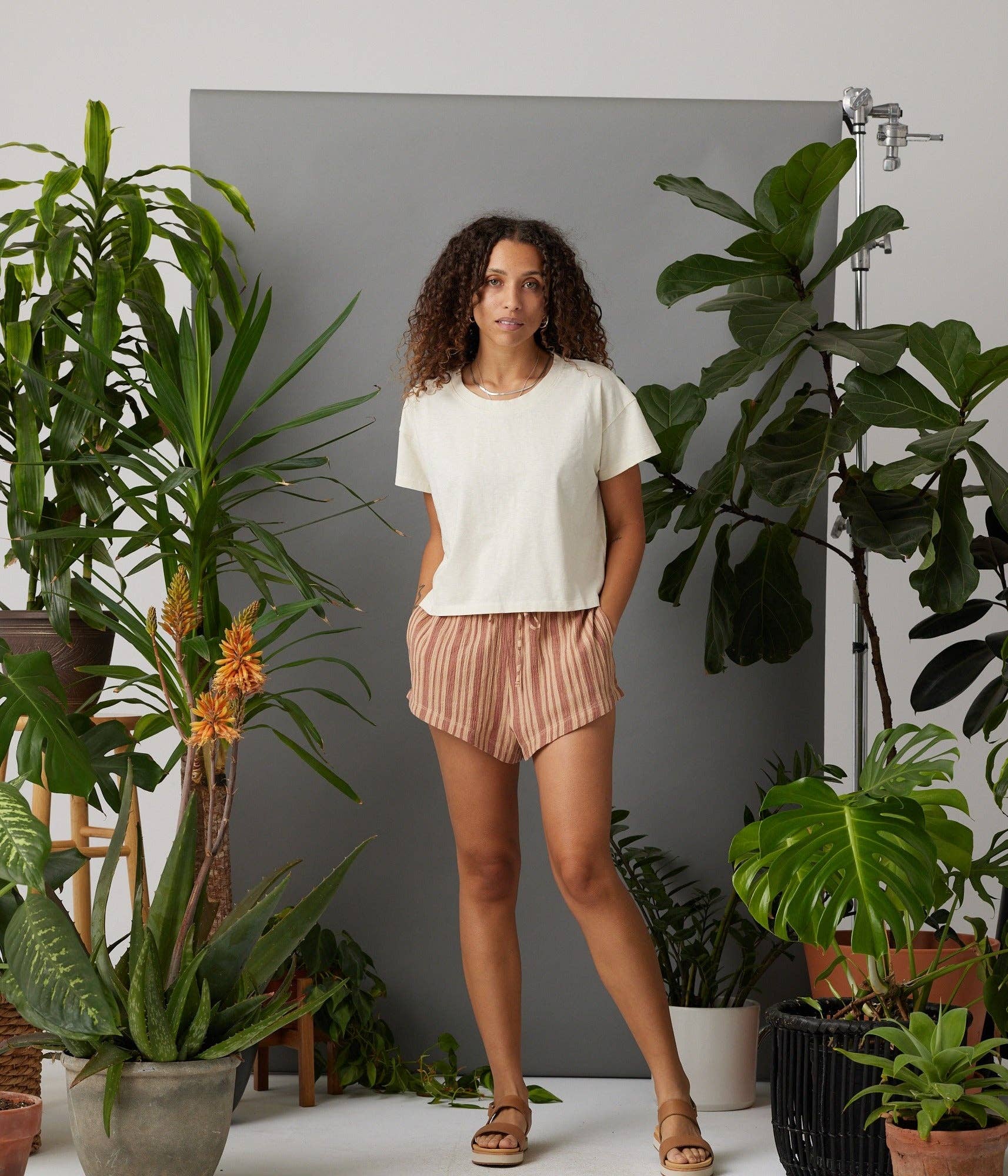 Woman standing among potted plants in a home setting