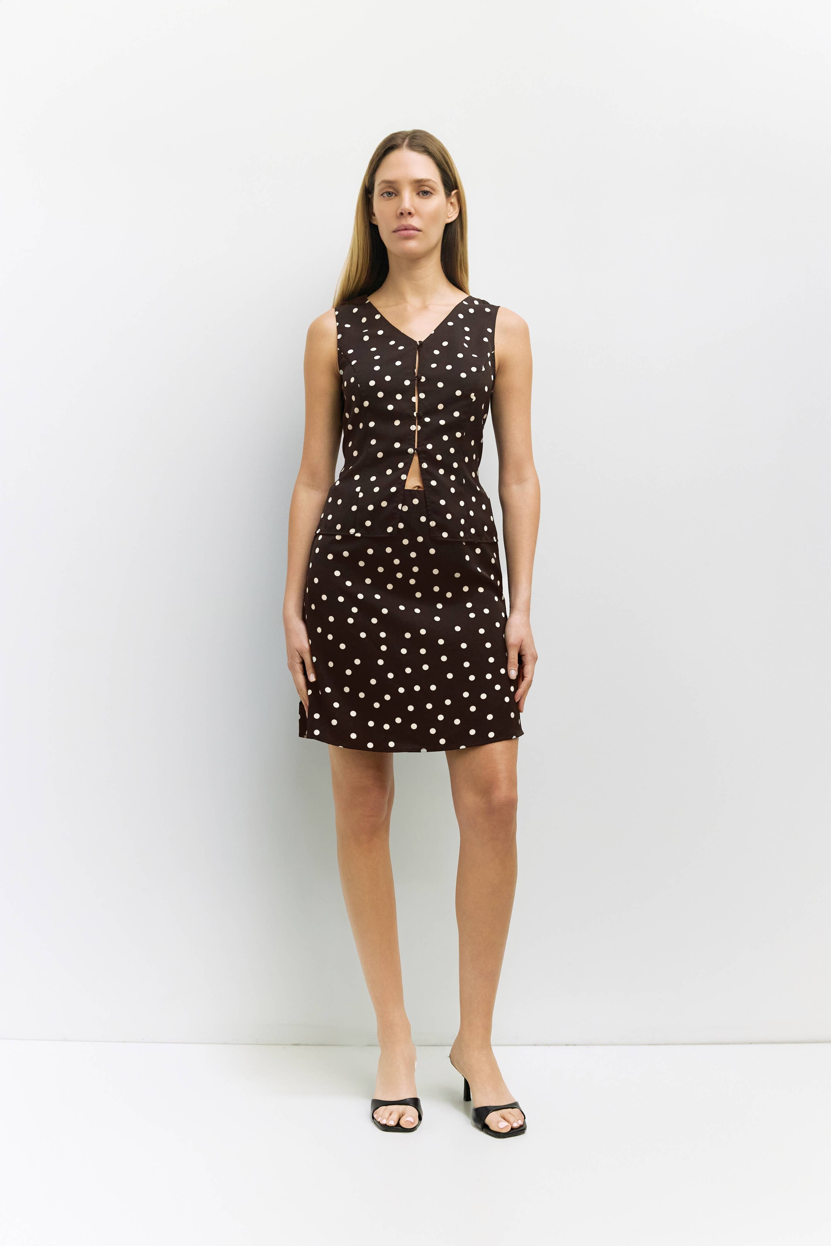 Woman wearing a brown top and skirt with white polka dots against a white background