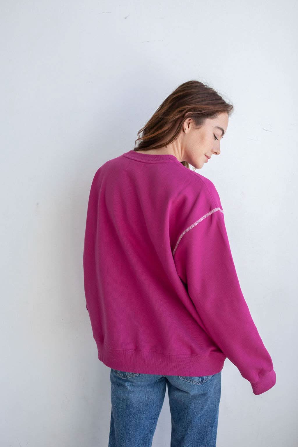 Woman wearing pinkish purple pullover with unique stitching details