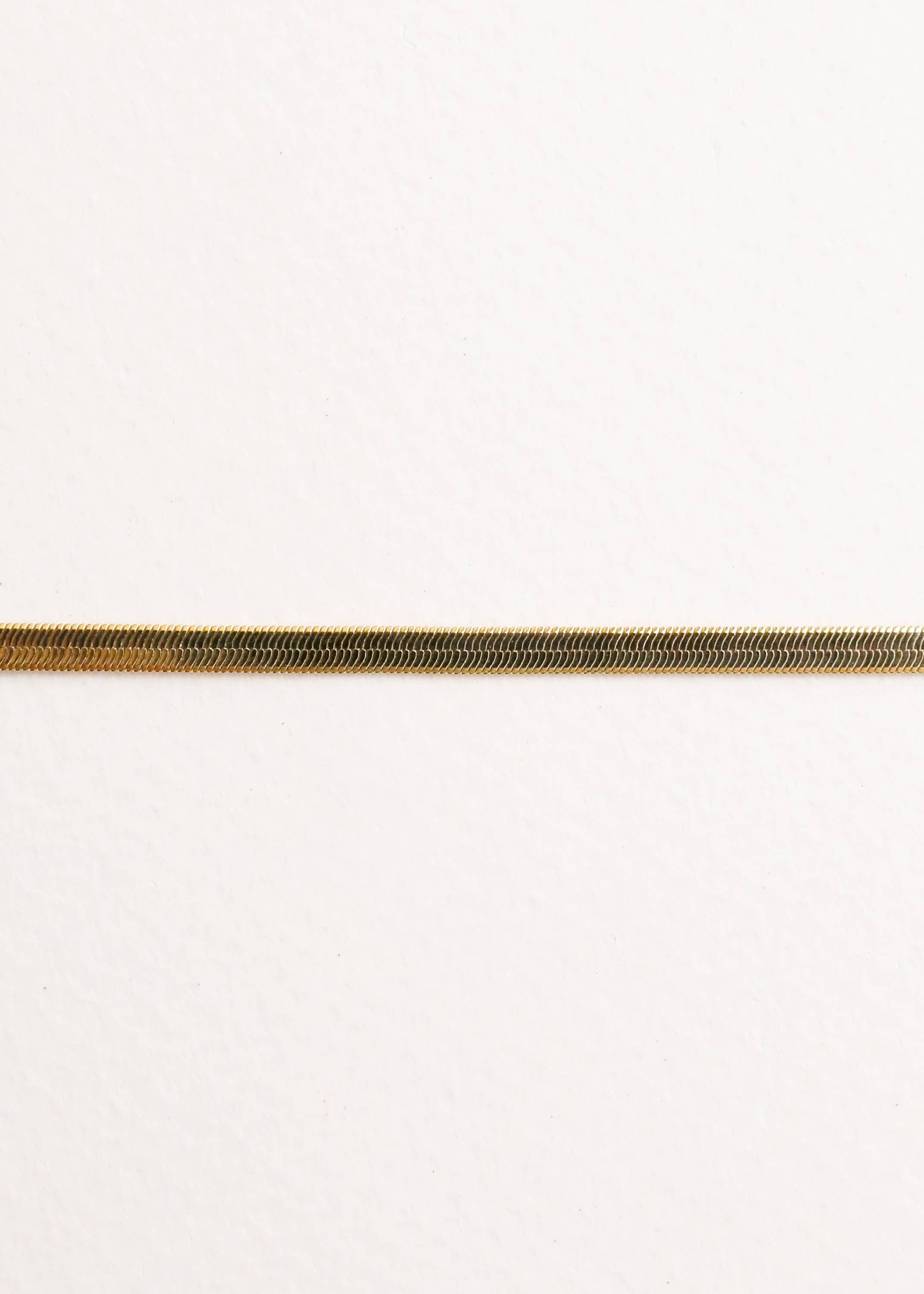 Close up of a gold bracelet on a white background