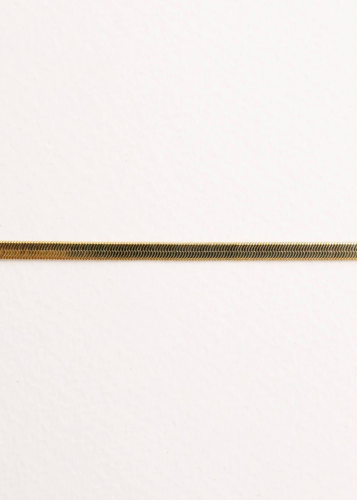 Close up of a gold bracelet on a white background