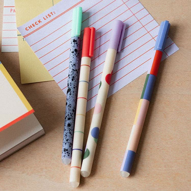 Four colorful pens laying on top of sticky notes on desk