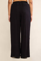 Woman facing away from the camera wearing black, wide leg, cove linen pant and white tee