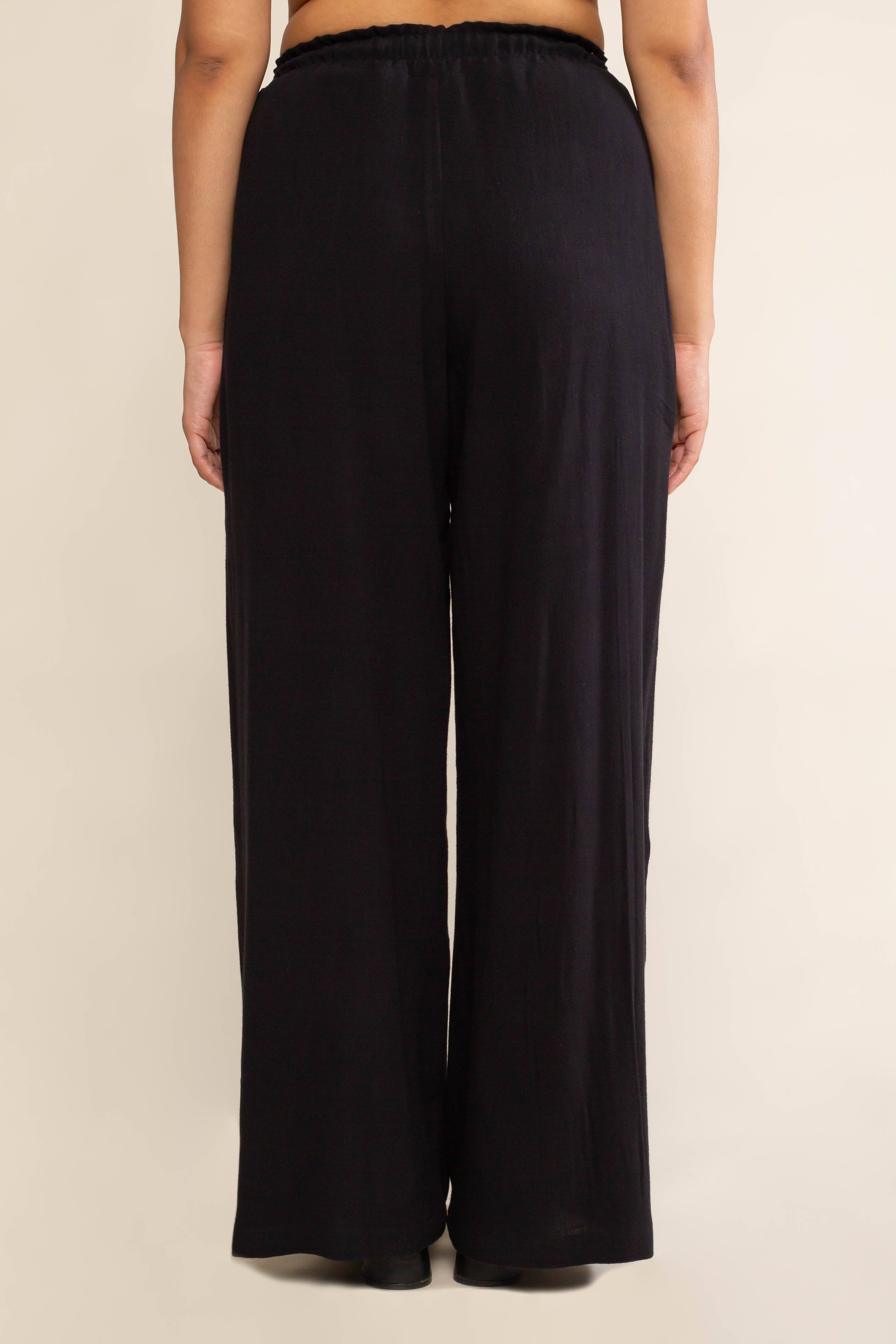Woman facing away from the camera wearing black, wide leg, cove linen pant and white tee