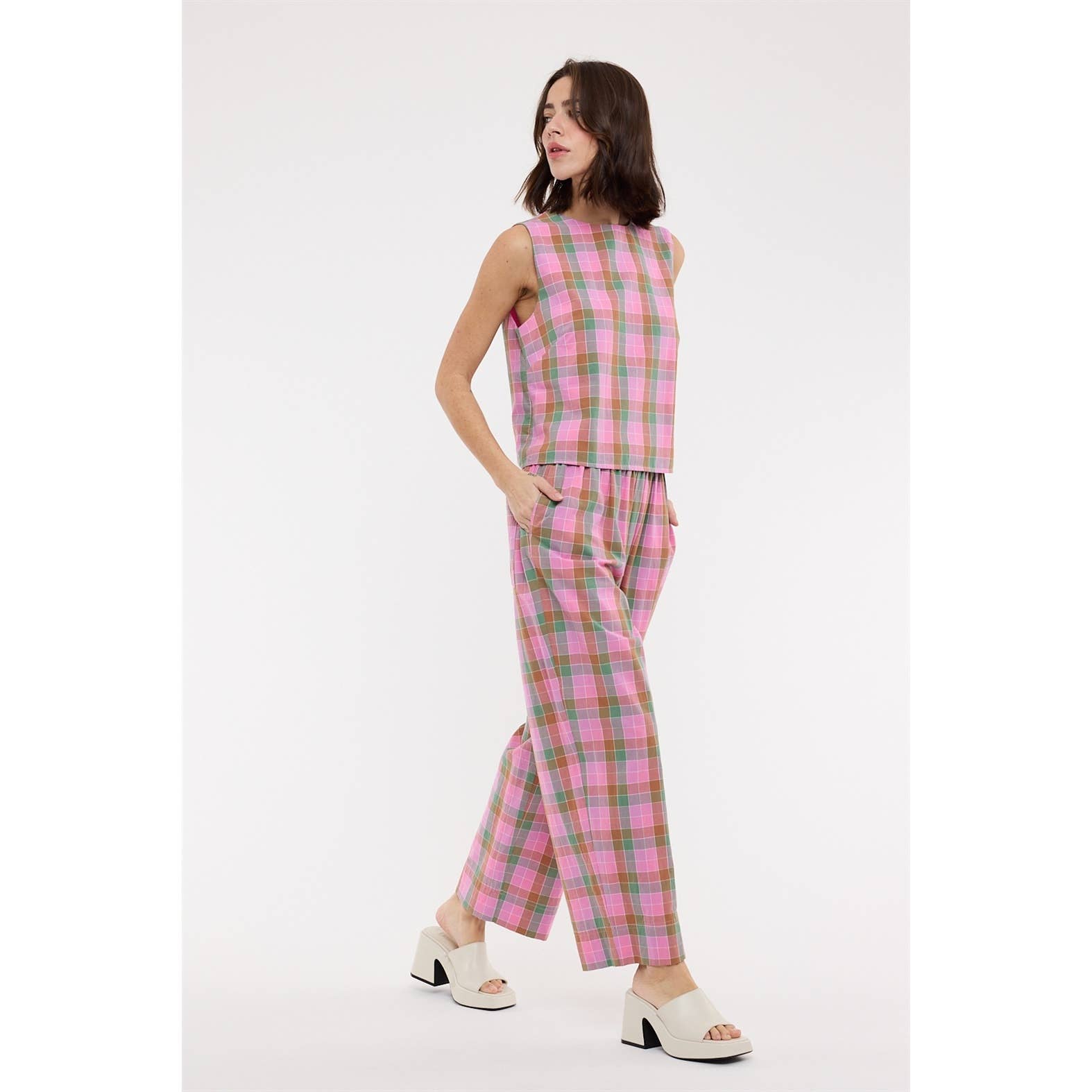 Woman wearing a pink plaid outfit on a white background
