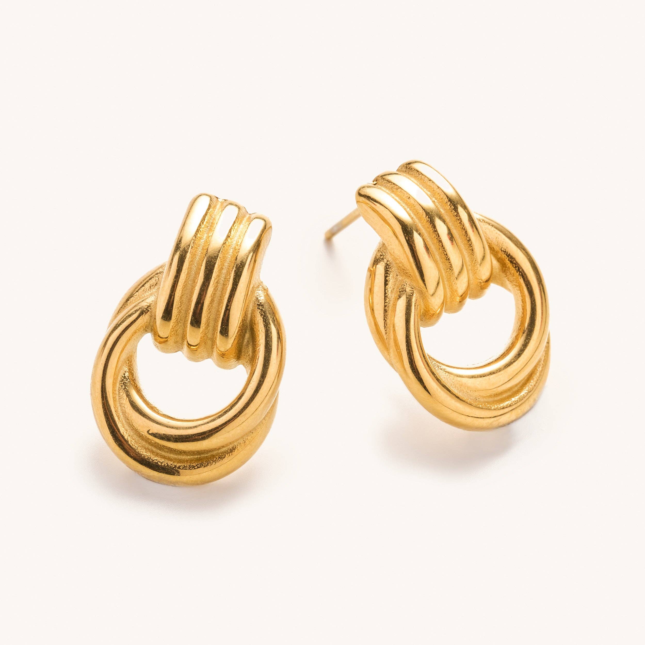 Pair of gold knot earring studs on a white background 