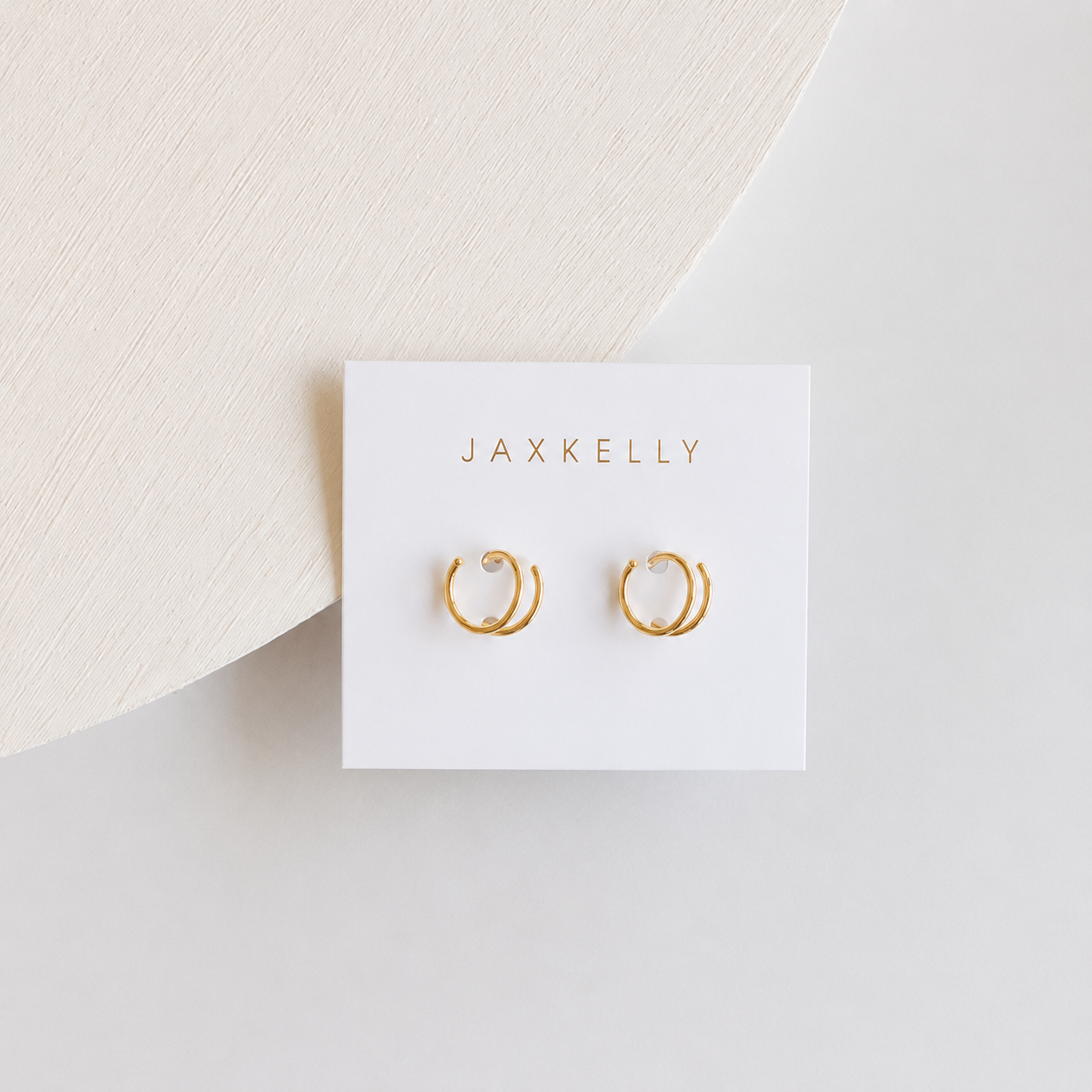 Gold hoop spiral earrings on a Jaxkelly branded card against a light background