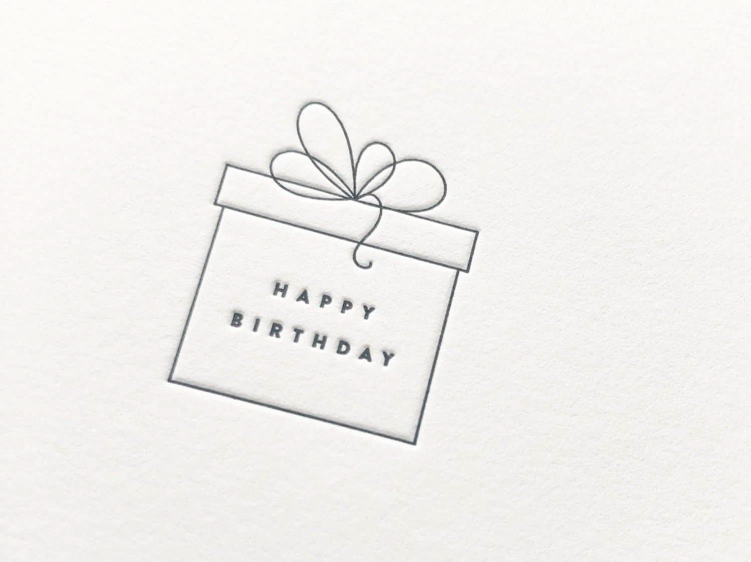 Happy birthday greeting card picturing black thin present box with ribbons