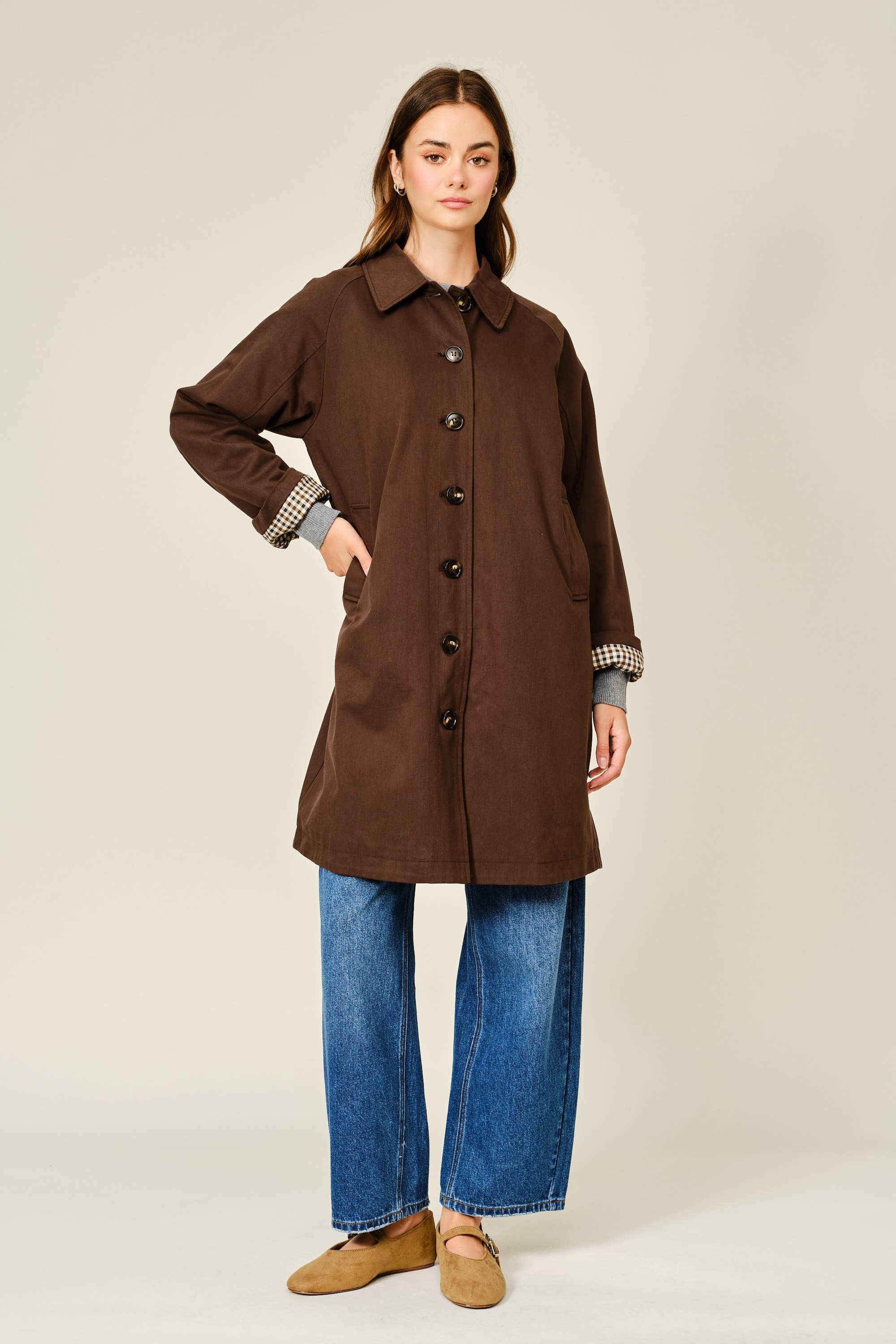 Woman wearing a brown coat with a plain background