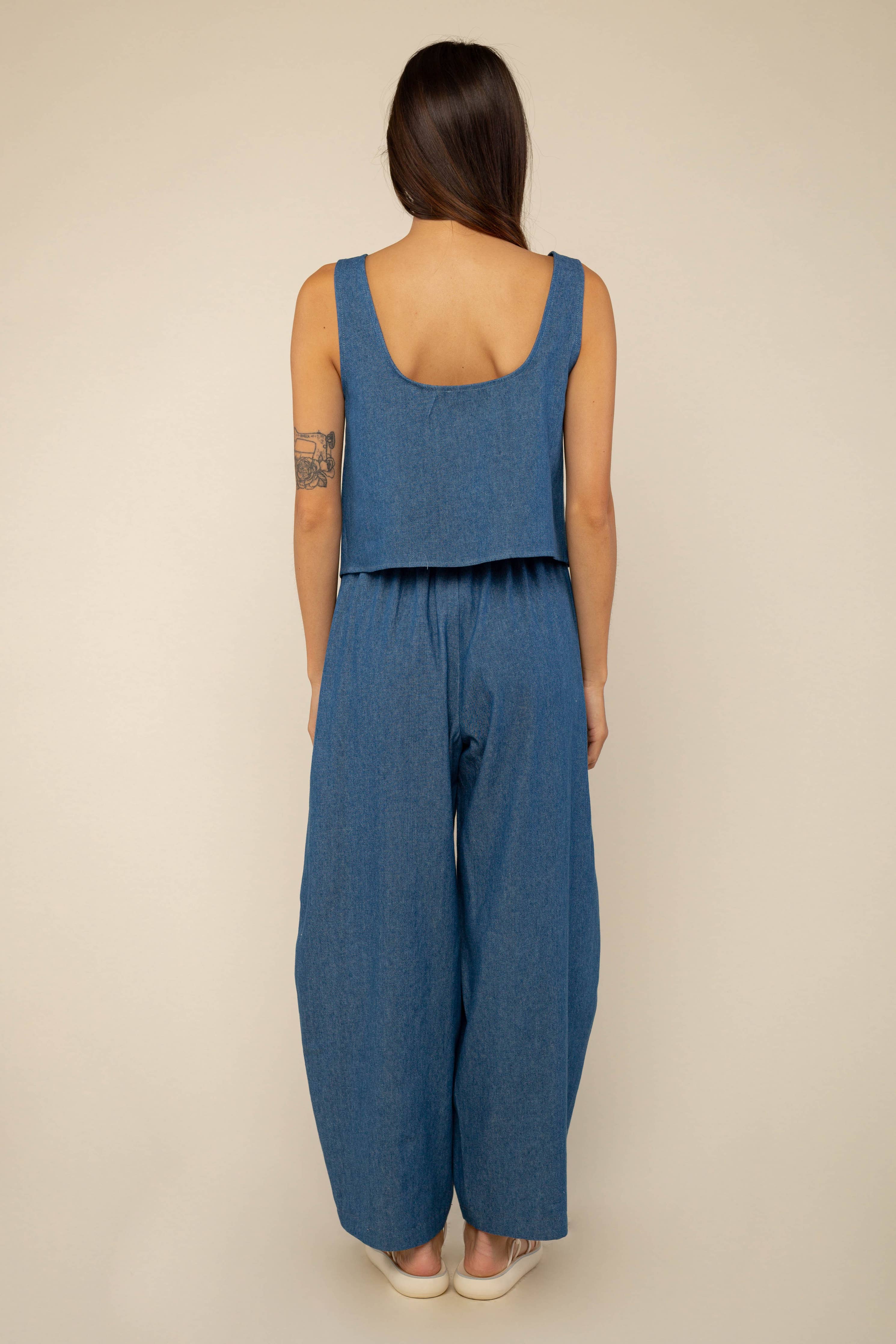 Woman facing away from the camera wearing denim, high rise, barrel jeans with a medium wash color and matching top 