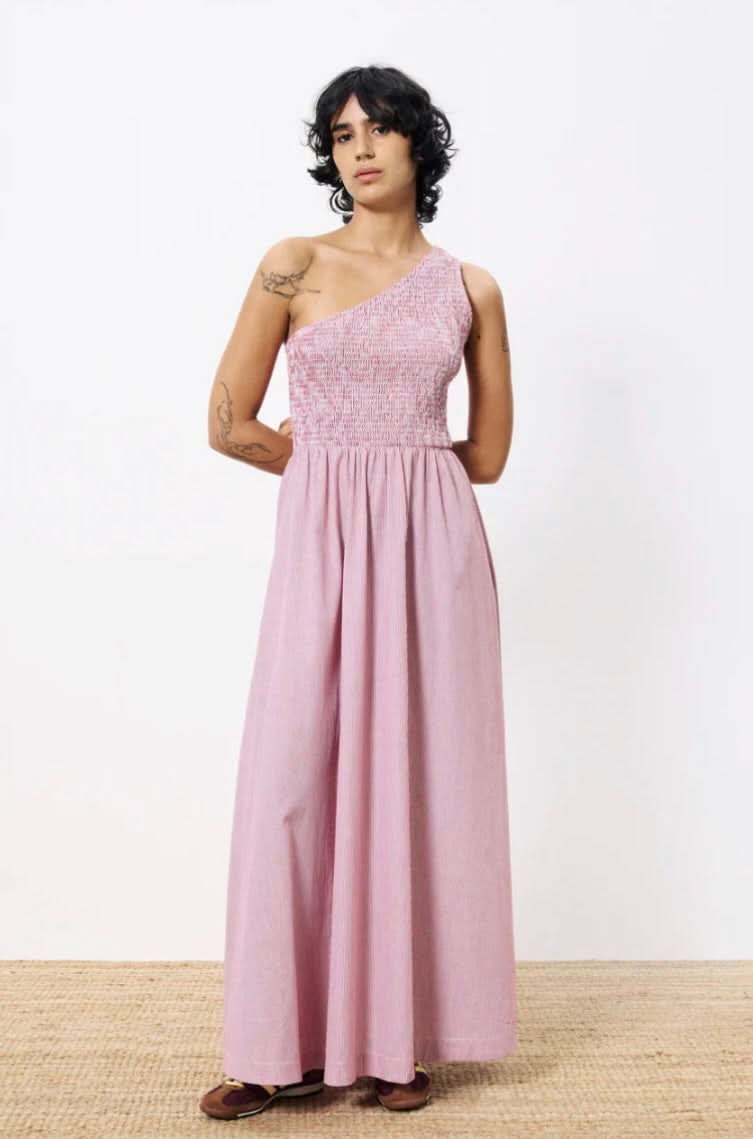 Woman wearing a pink one-shoulder dress against a white background