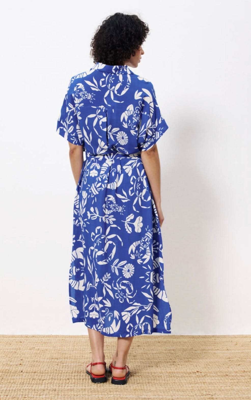 Woman wearing a blue floral dress against a white background