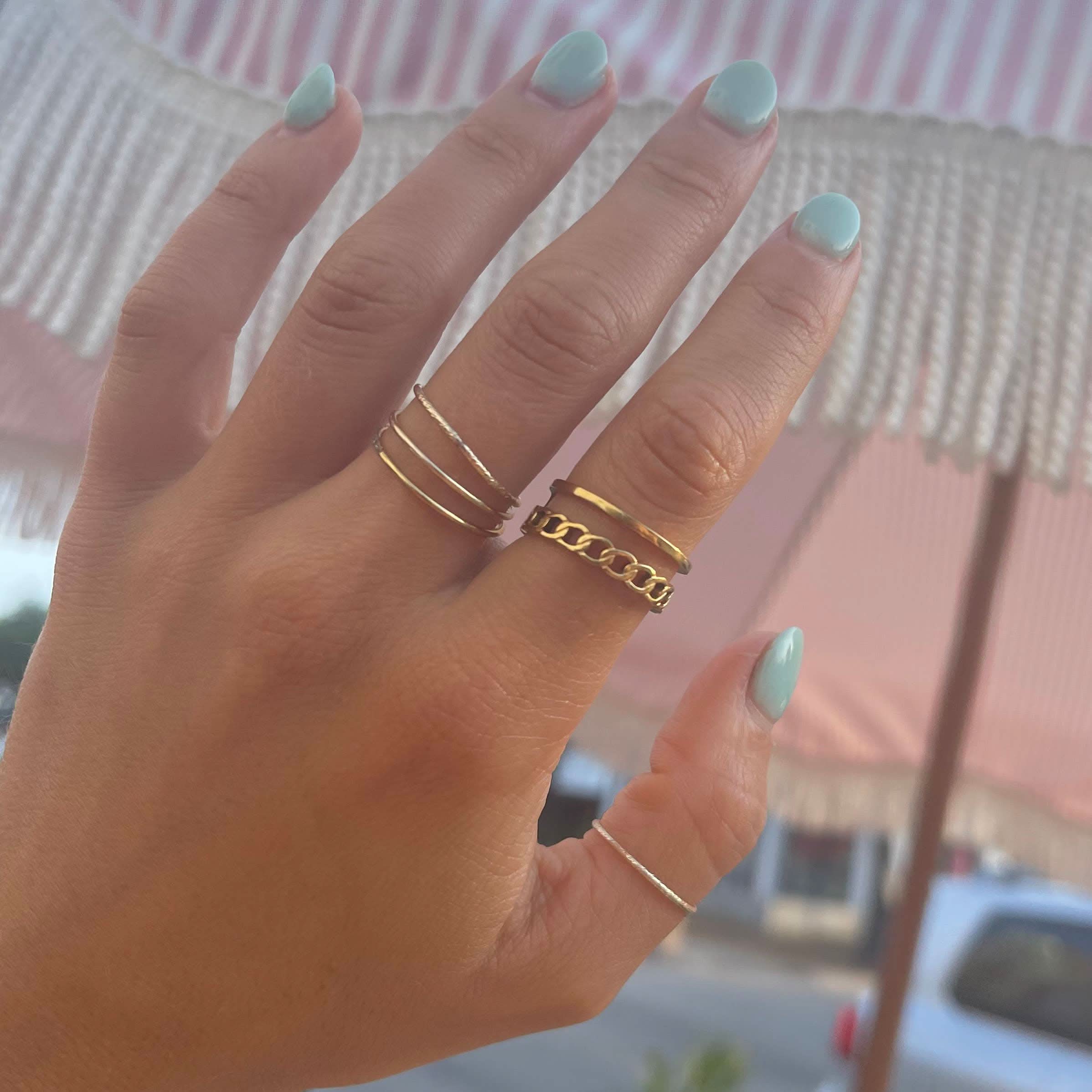 Woman wearing Simple thin gold ring in a stack with other gold rings 