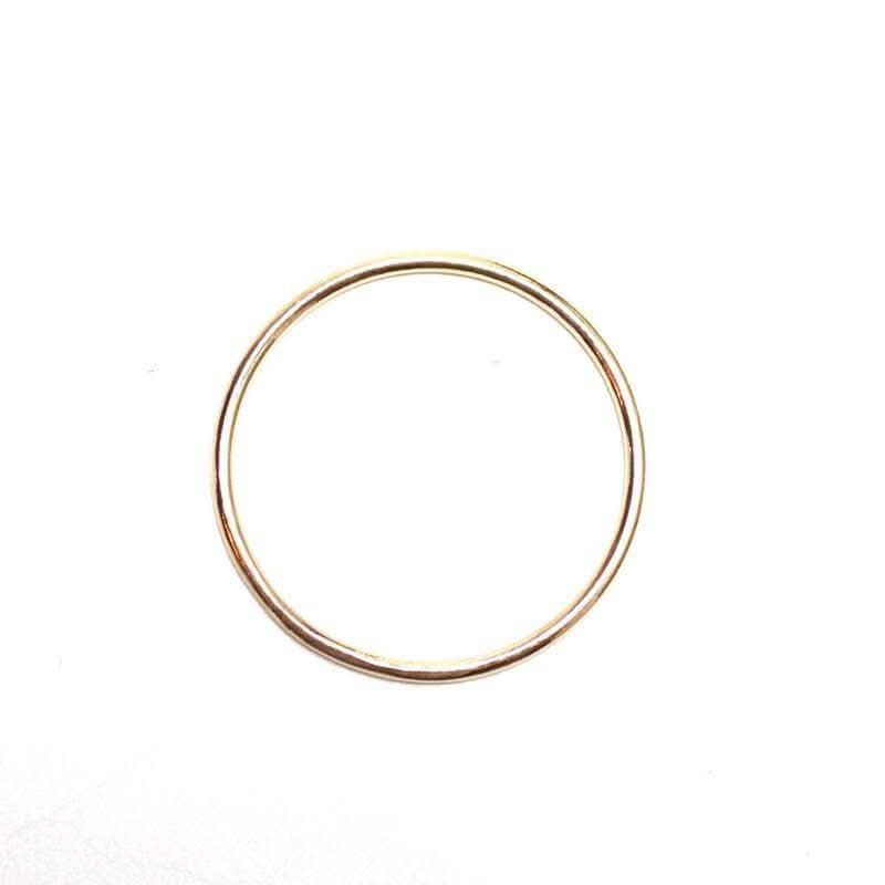 Simple thin gold ring for stacking laying on a white background 