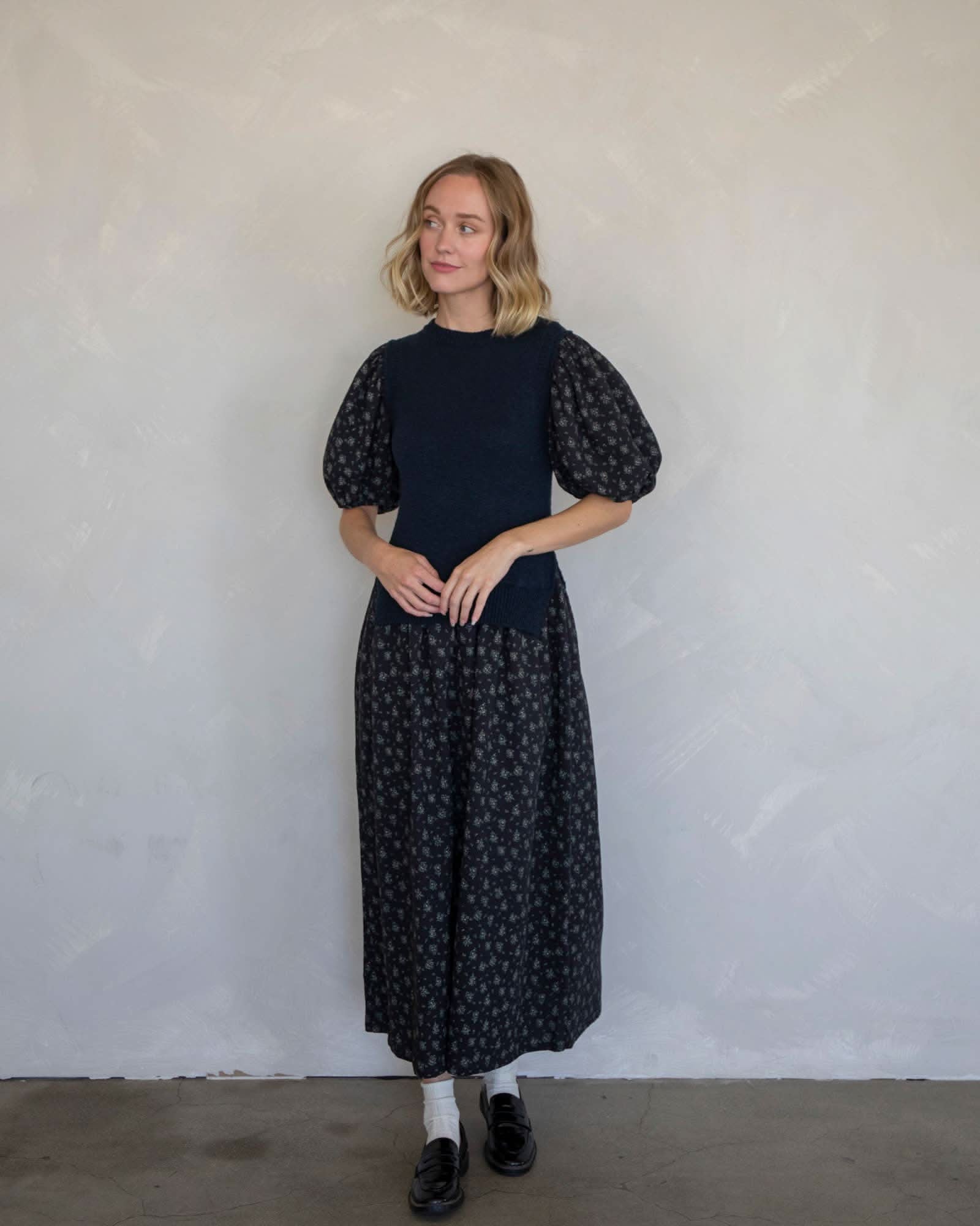 Keri Floral Sweater Vest Dress Woman wearing a black dress with puff sleeves