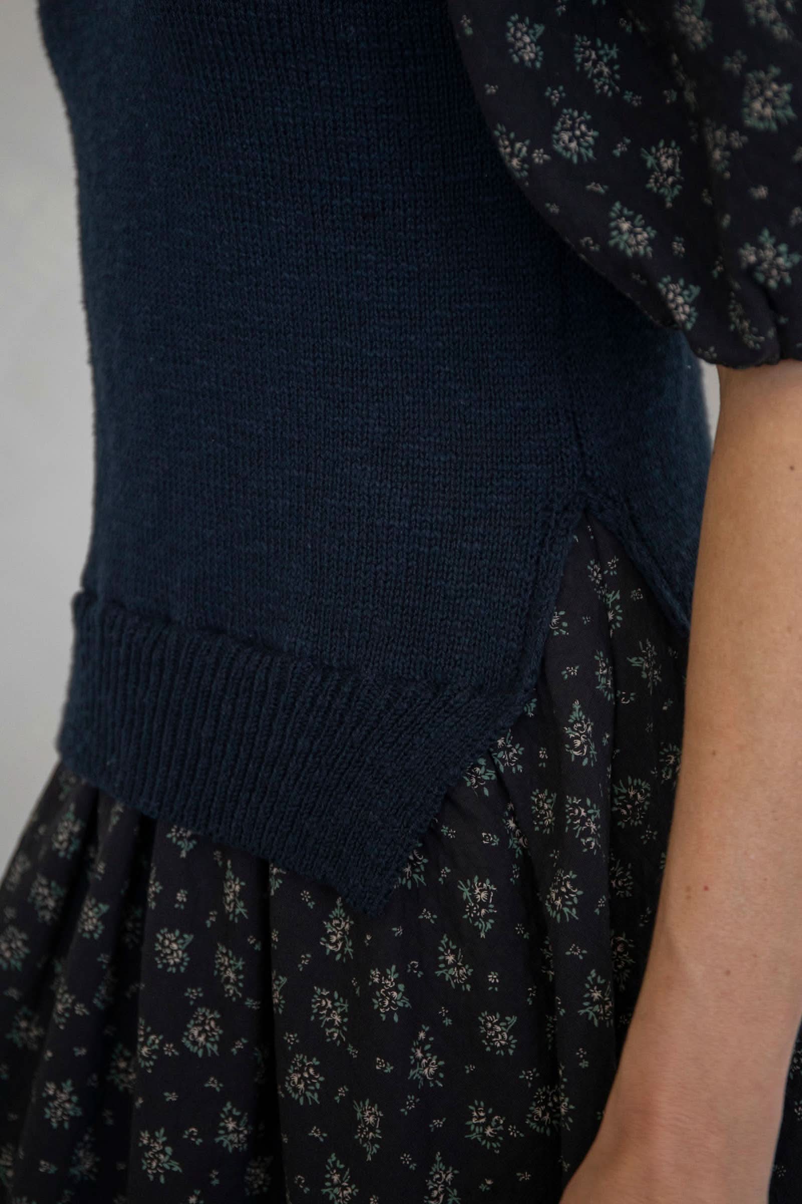Navy blue knitted cardigan over a patterned dress on a neutral background