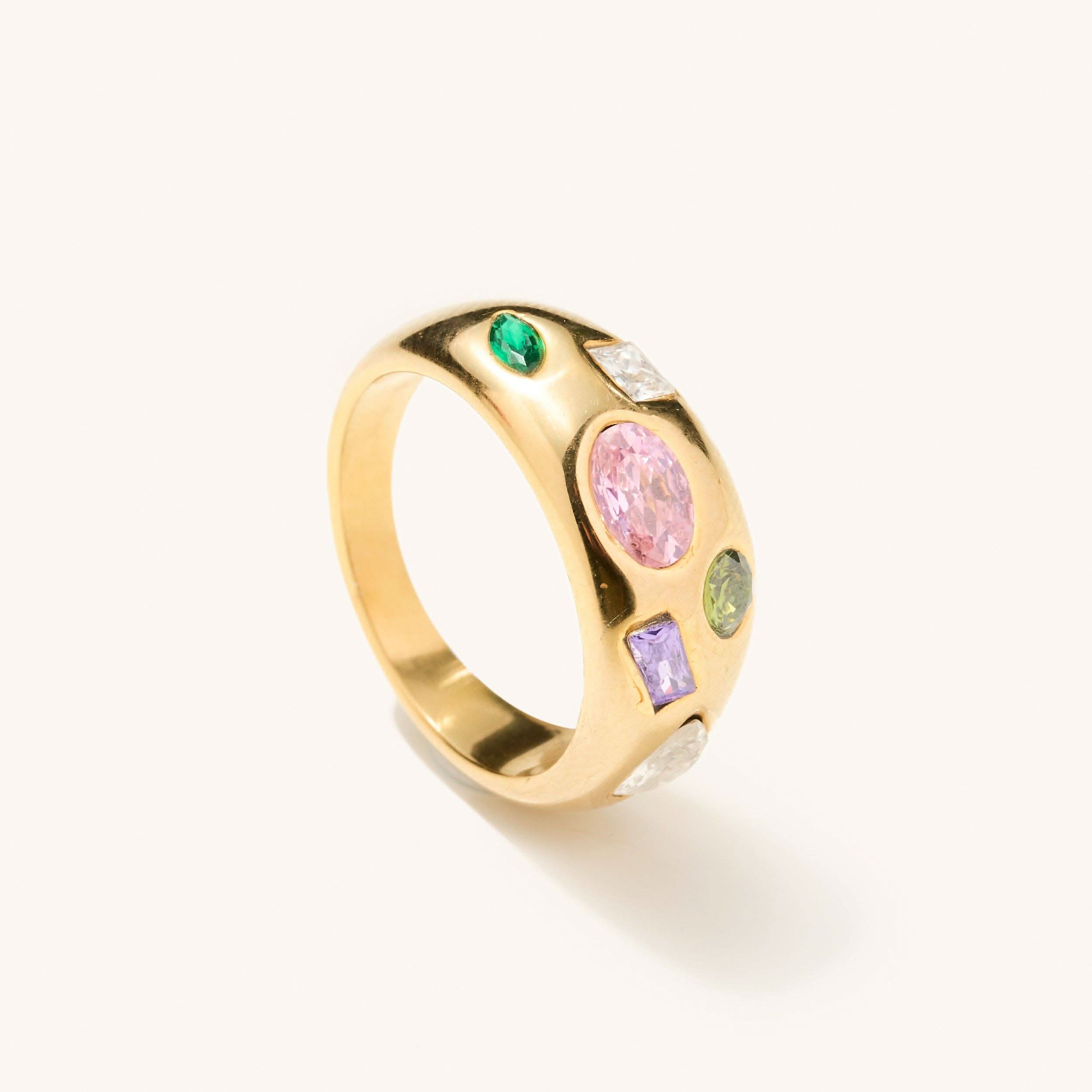 Gold ring with multi shaped and colored gems across the thickest head of the ring 