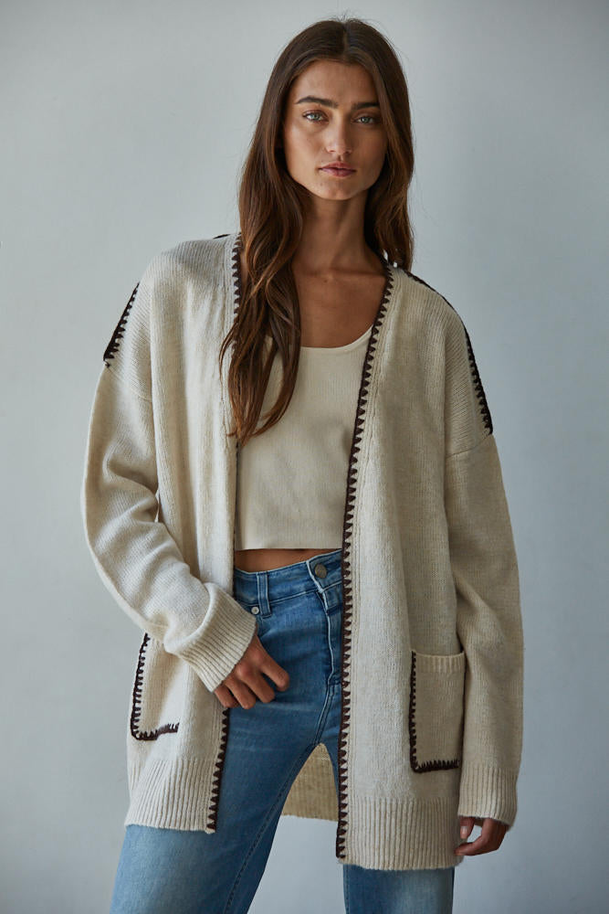 Woman wearing a Lotte Contrast Stitch Open Cardigan with black trim, white top