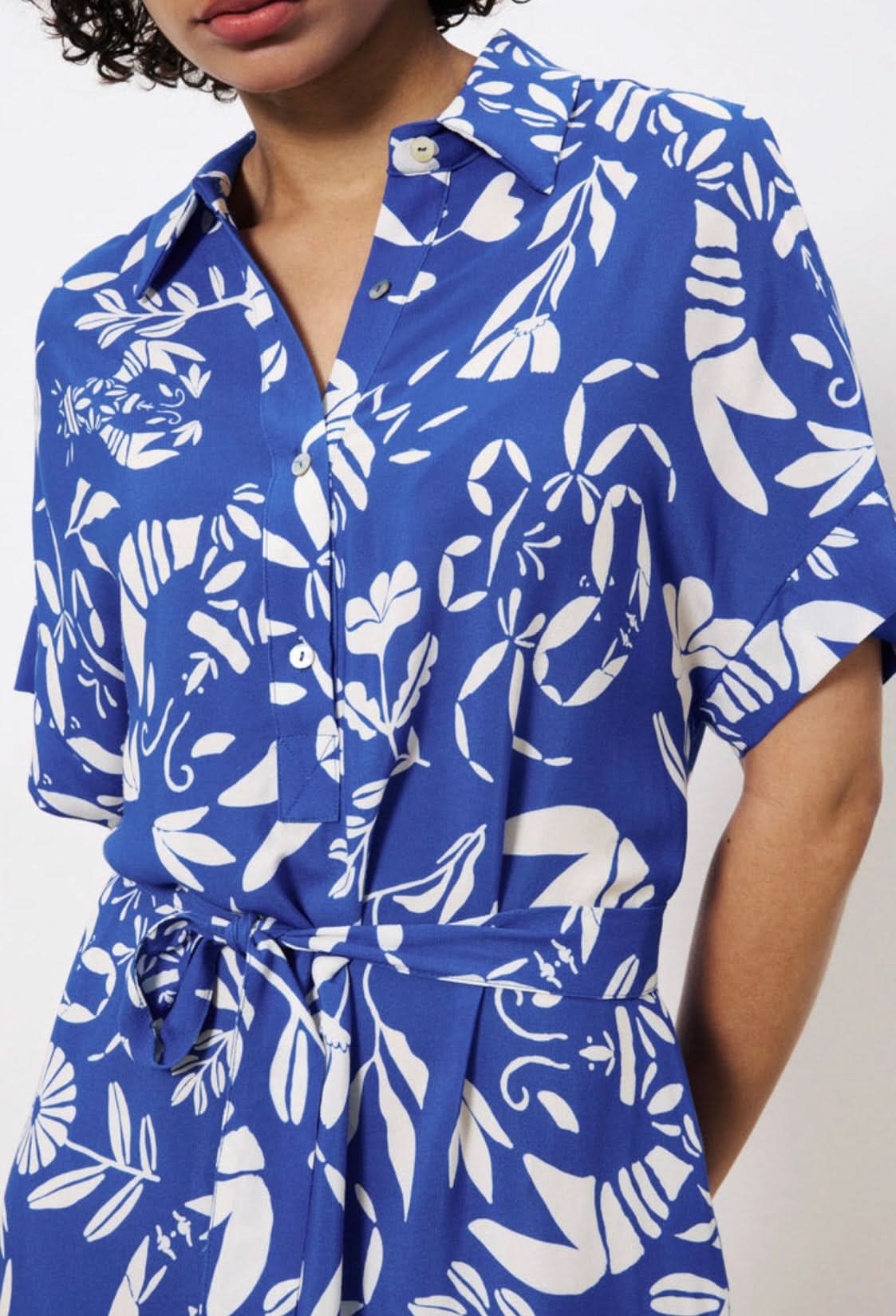Blue and white floral patterned shirt worn by a person on a plain background