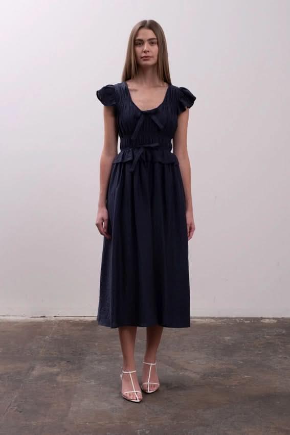 Woman wearing a dark blue dress Moon River Shirred Ruffle Midi Dress