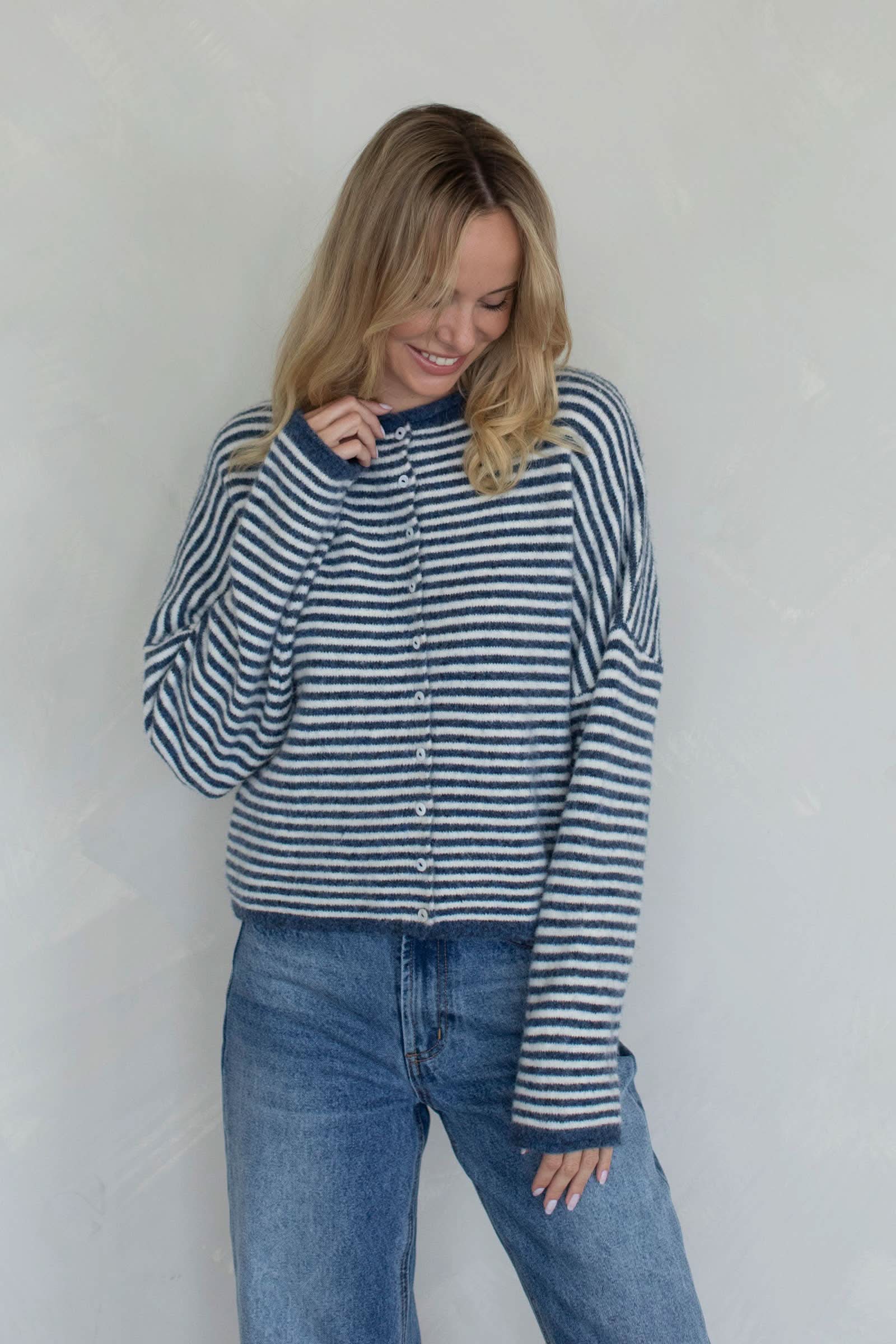 Woman wearing a white and blue striped sweater with small buttons