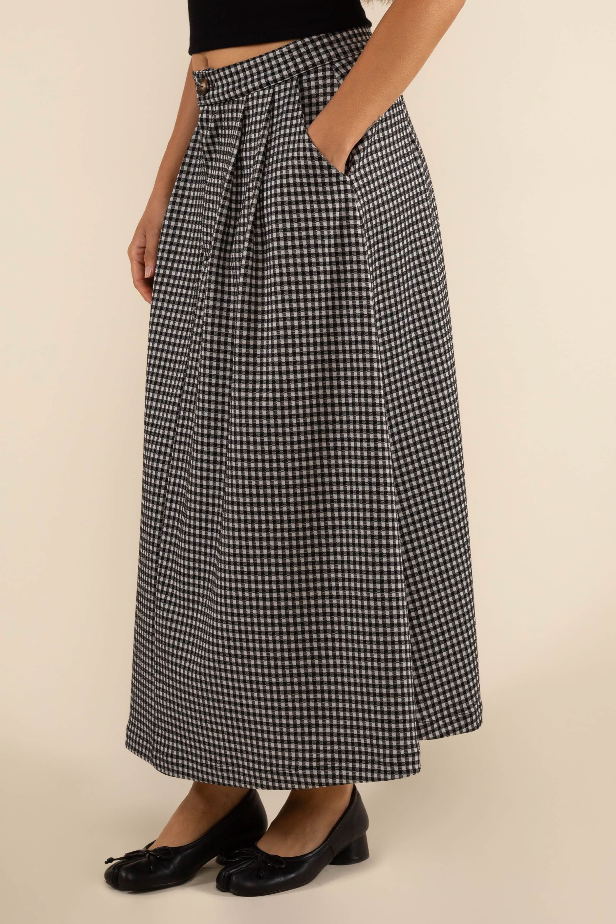 Person wearing checkered skirt with pleats at the front and side pockets.
