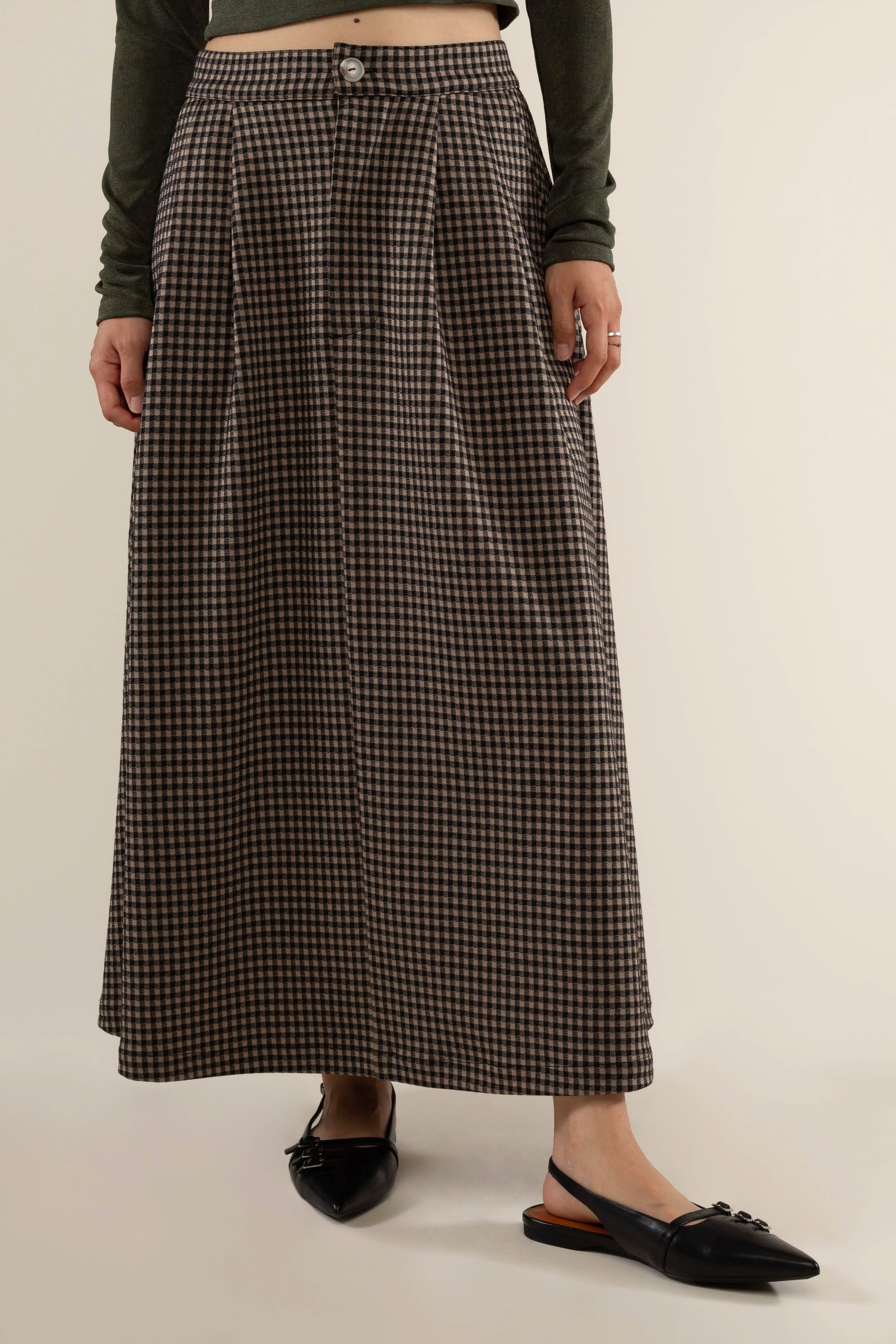 Person wearing a long plaid skirt with pleats at the front and side pockets.