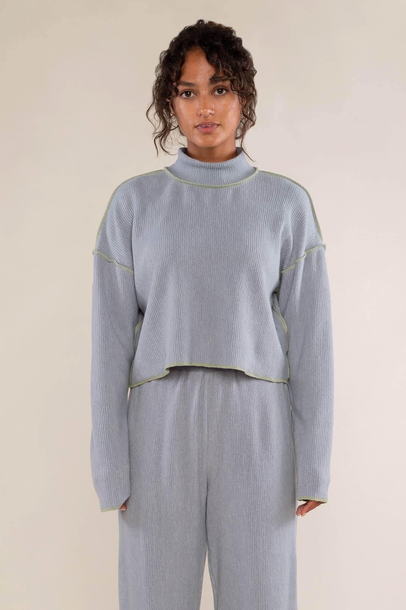 Woman wearing a light blue ribbed sweater and pants 