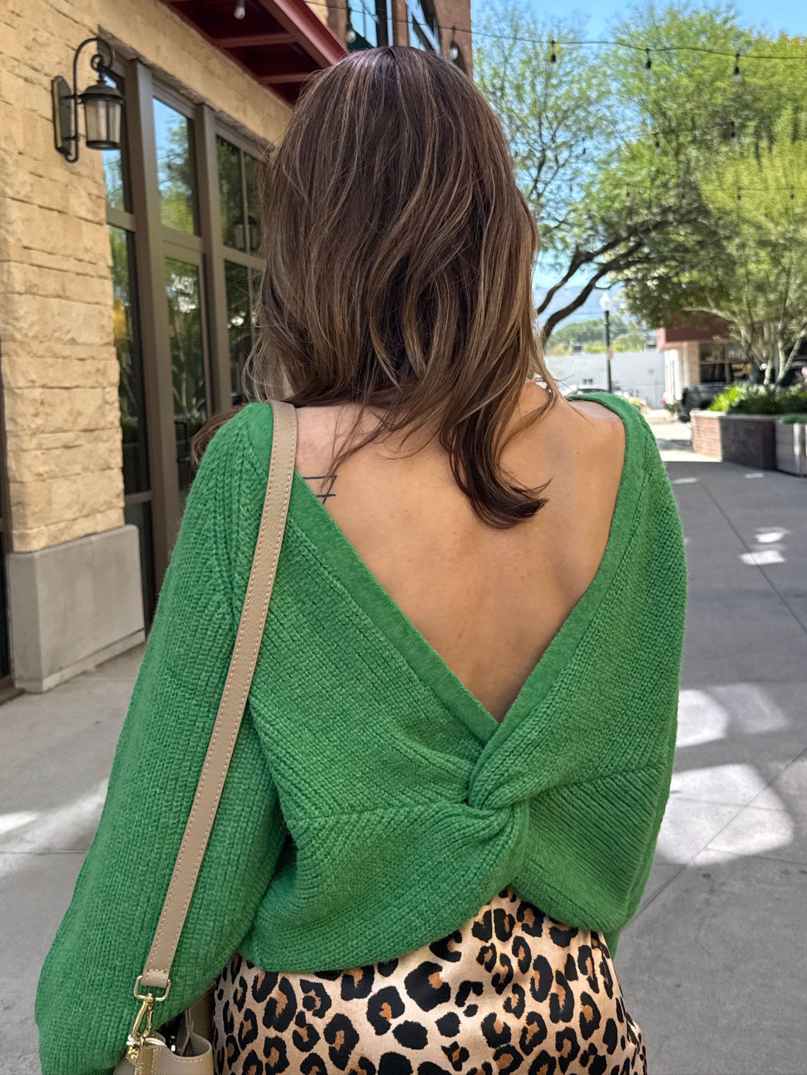 Woman wearing a green open-back sweater and leopard print skirt 